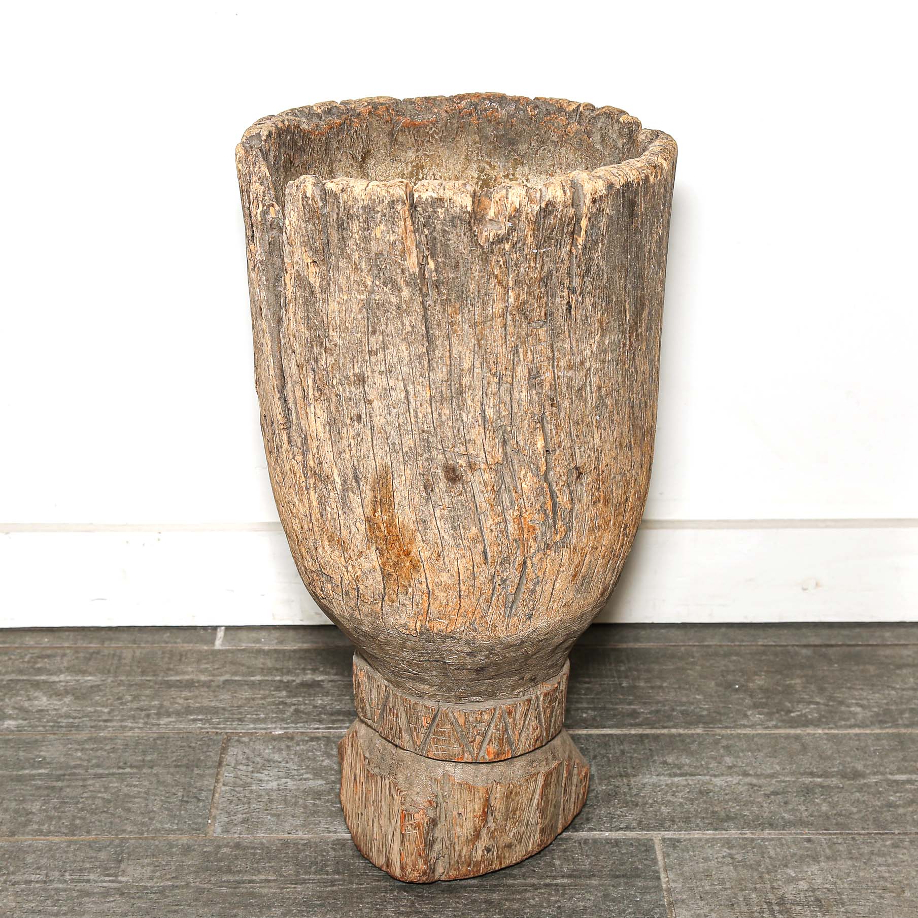 Wooden planter with textured surface on a gray floor