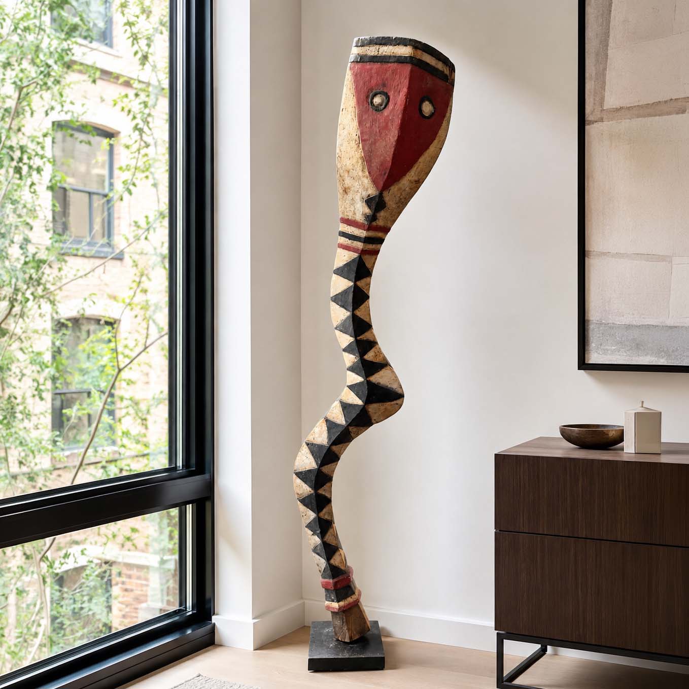Decorative tribal sculpture in a modern interior setting with a window and sideboard.