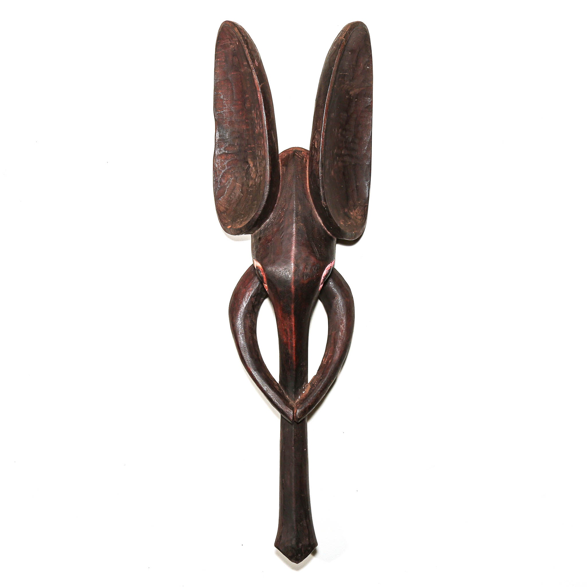 A dark brown carved wooden wall elephant mask with a stylized, abstract design featuring two upright loops at the top and a curved lower section, shown against a plain white background.