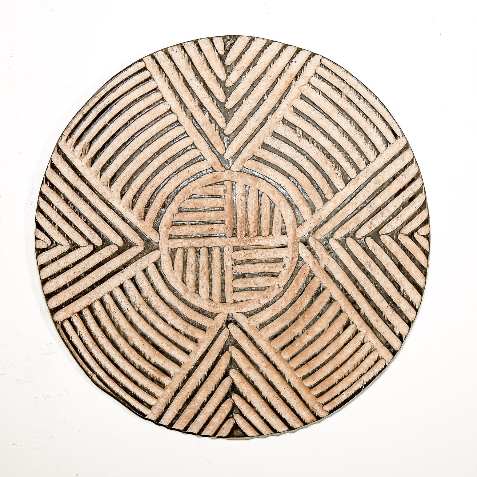 Round wood wall decor with rustic African traditional striped pattern on a white living room wall