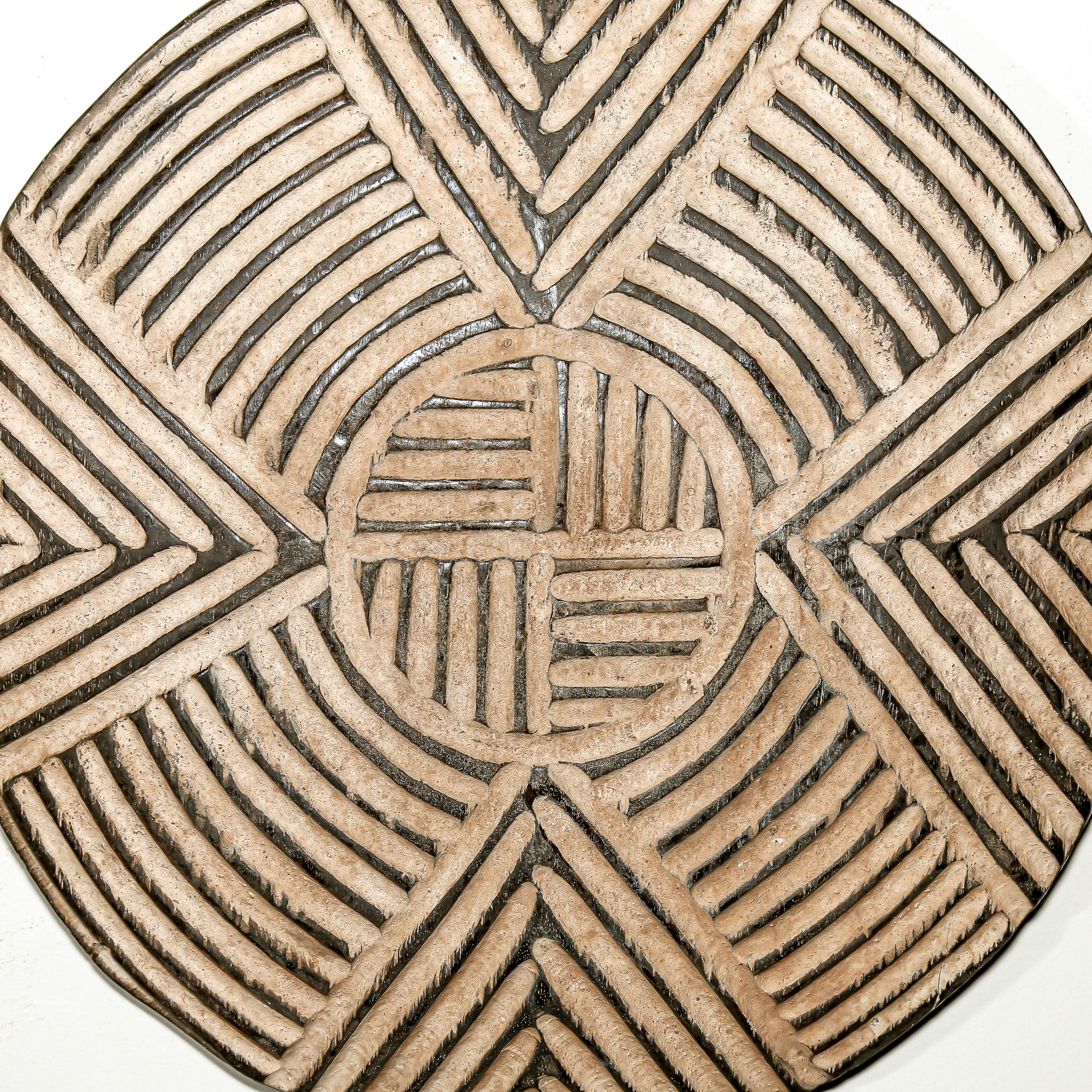 Round wood wall decor with rustic African traditional striped pattern on a white living room wall