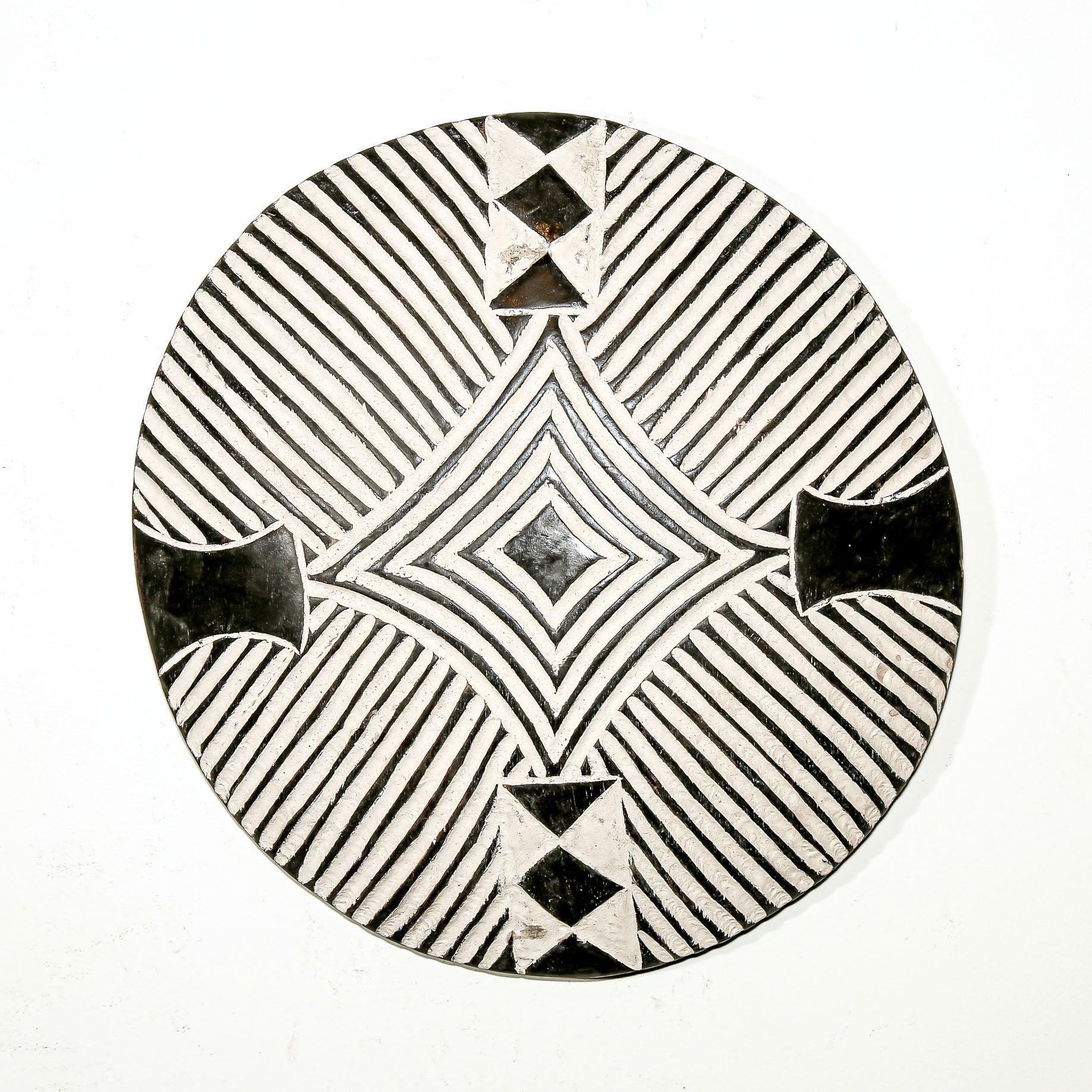 Round wood wall decor with rustic African traditional striped pattern on a white living room wall