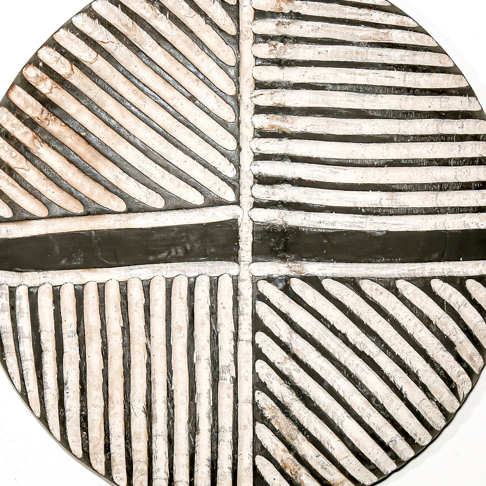 Round wood wall decor with rustic African traditional striped pattern on a white living room wall