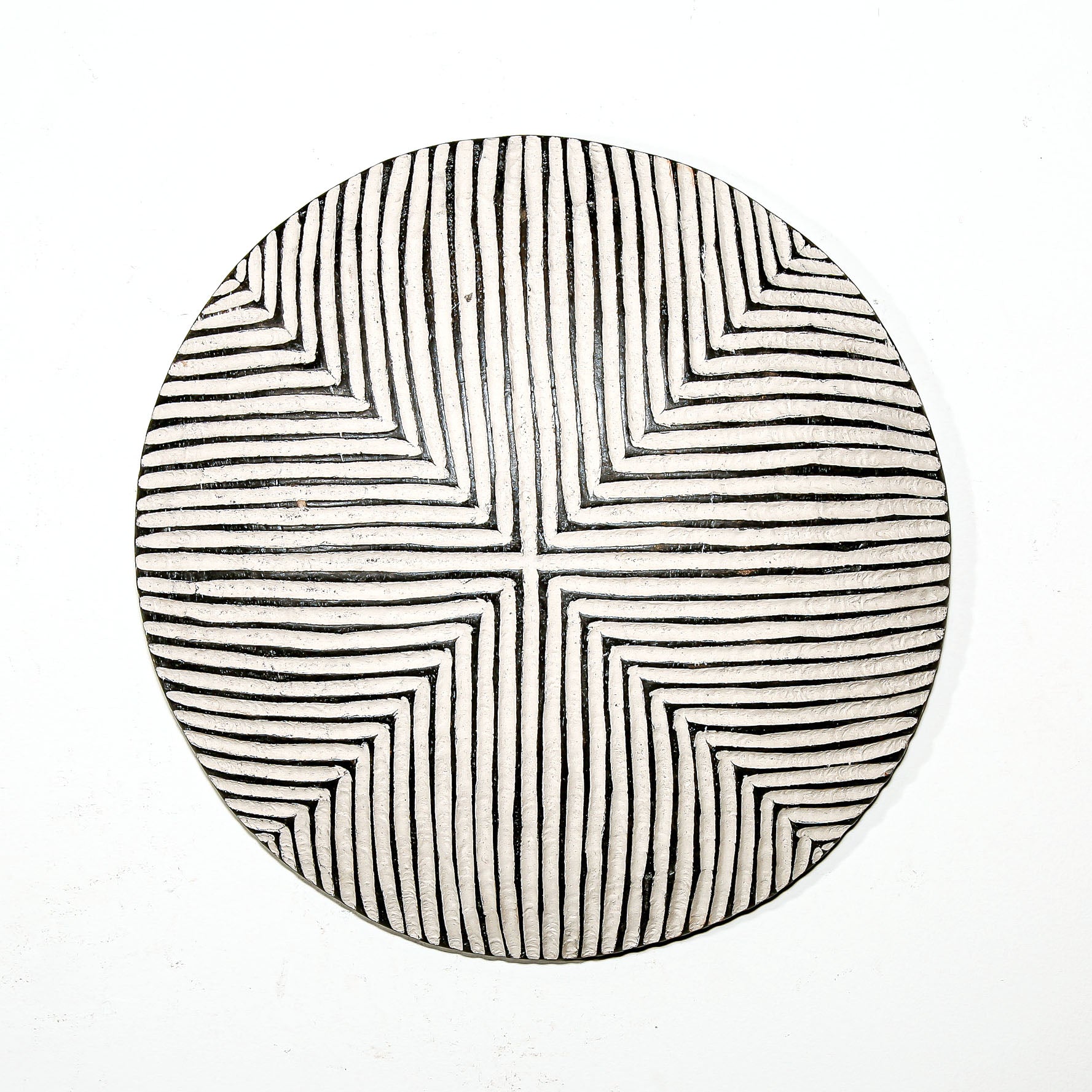 Round wood wall decor with rustic African traditional striped pattern on a white living room wall