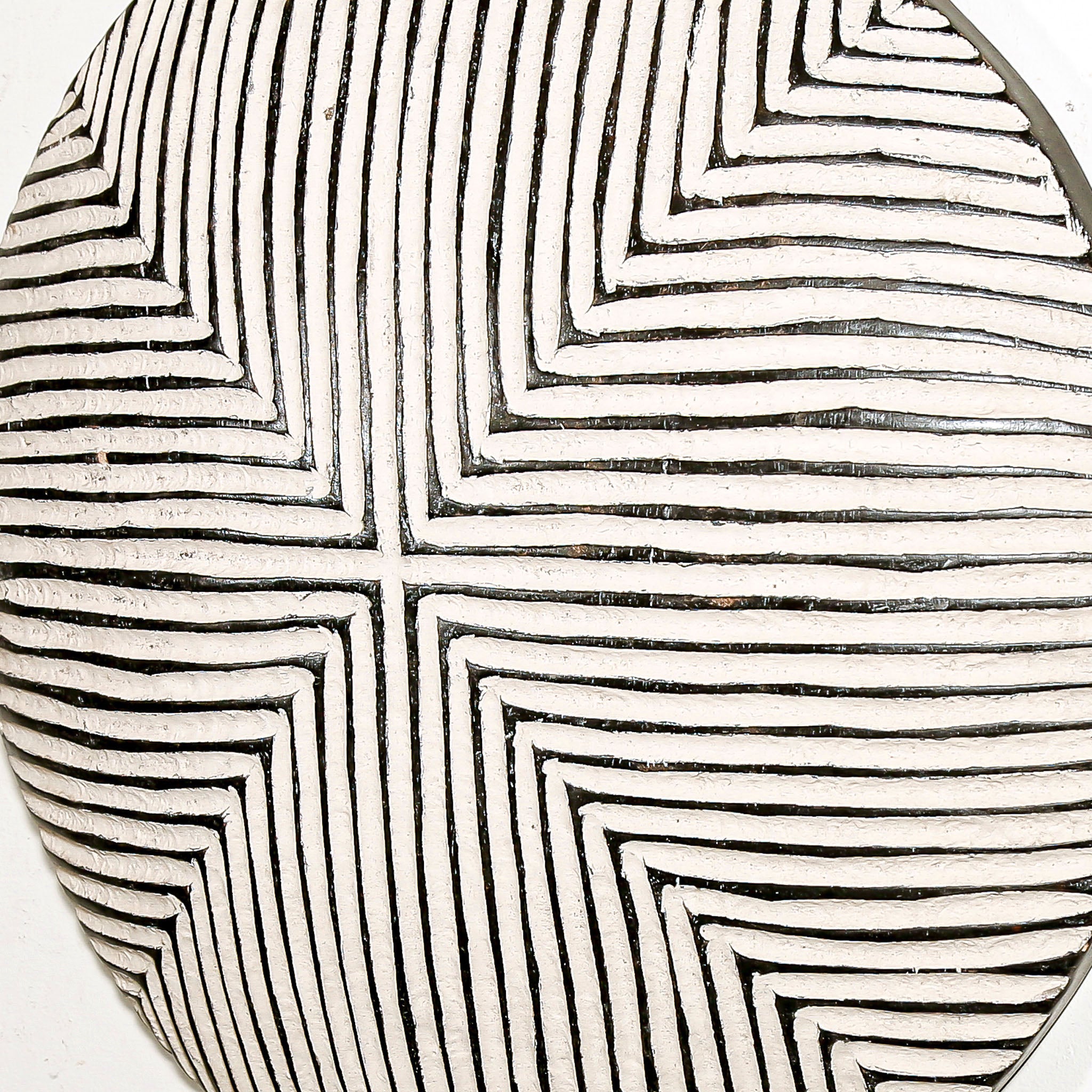 Round wood wall decor with rustic African traditional striped pattern on a white living room wall