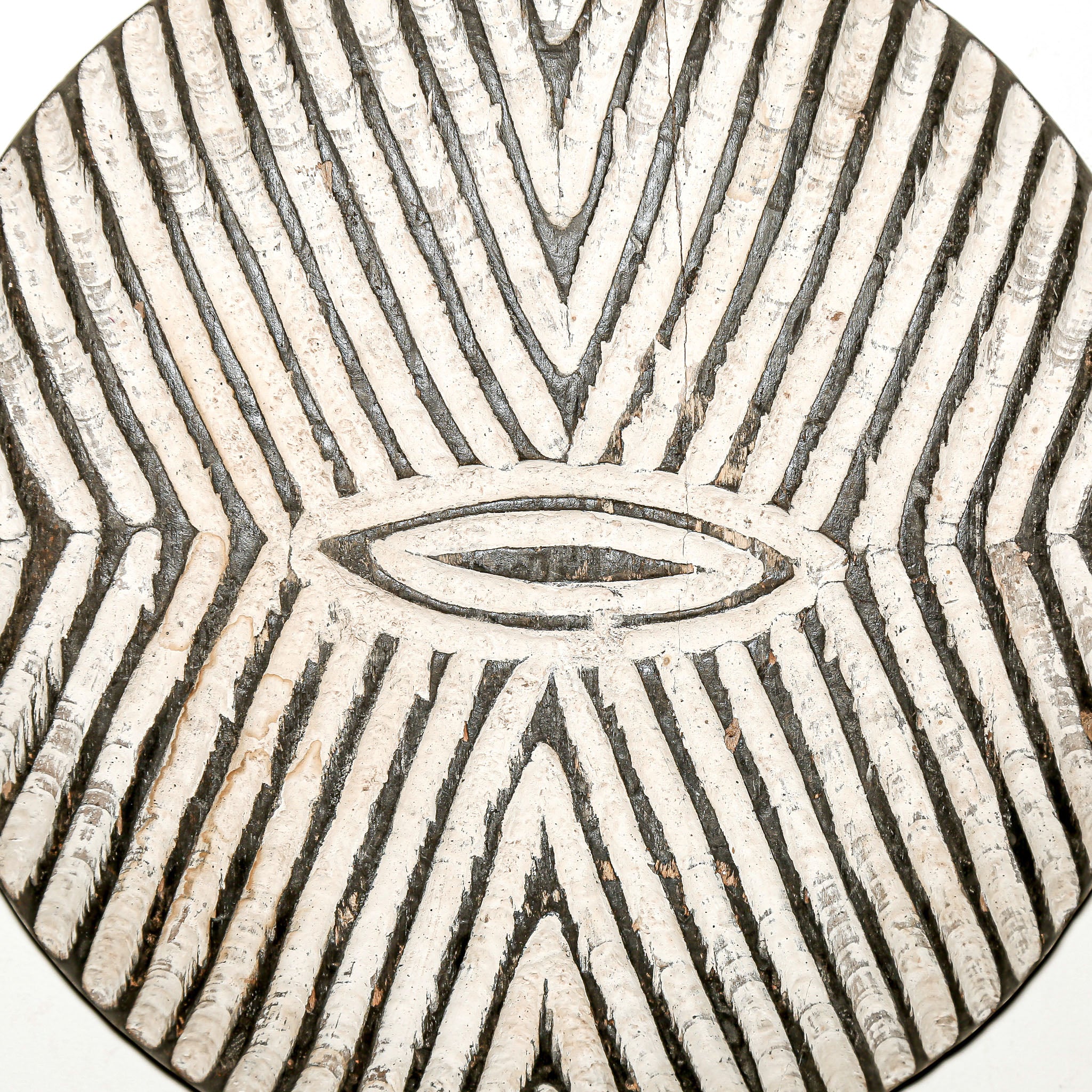 Round wood wall decor with rustic African traditional striped pattern on a white living room wall