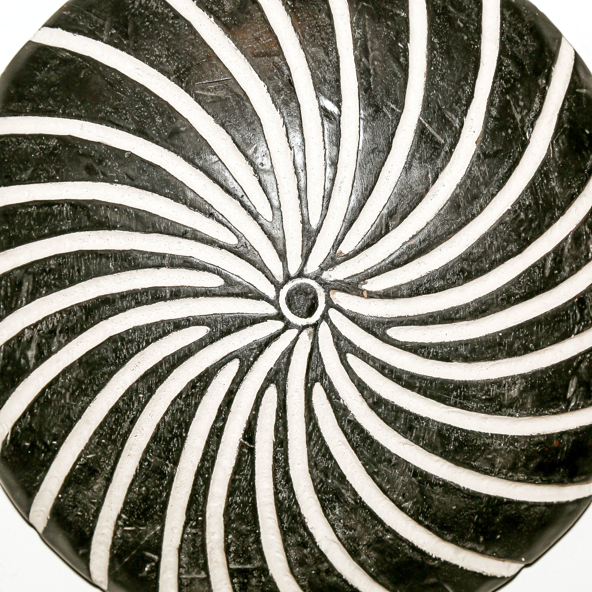 Round wood wall decor with rustic African traditional spiral pattern on a white living room wall