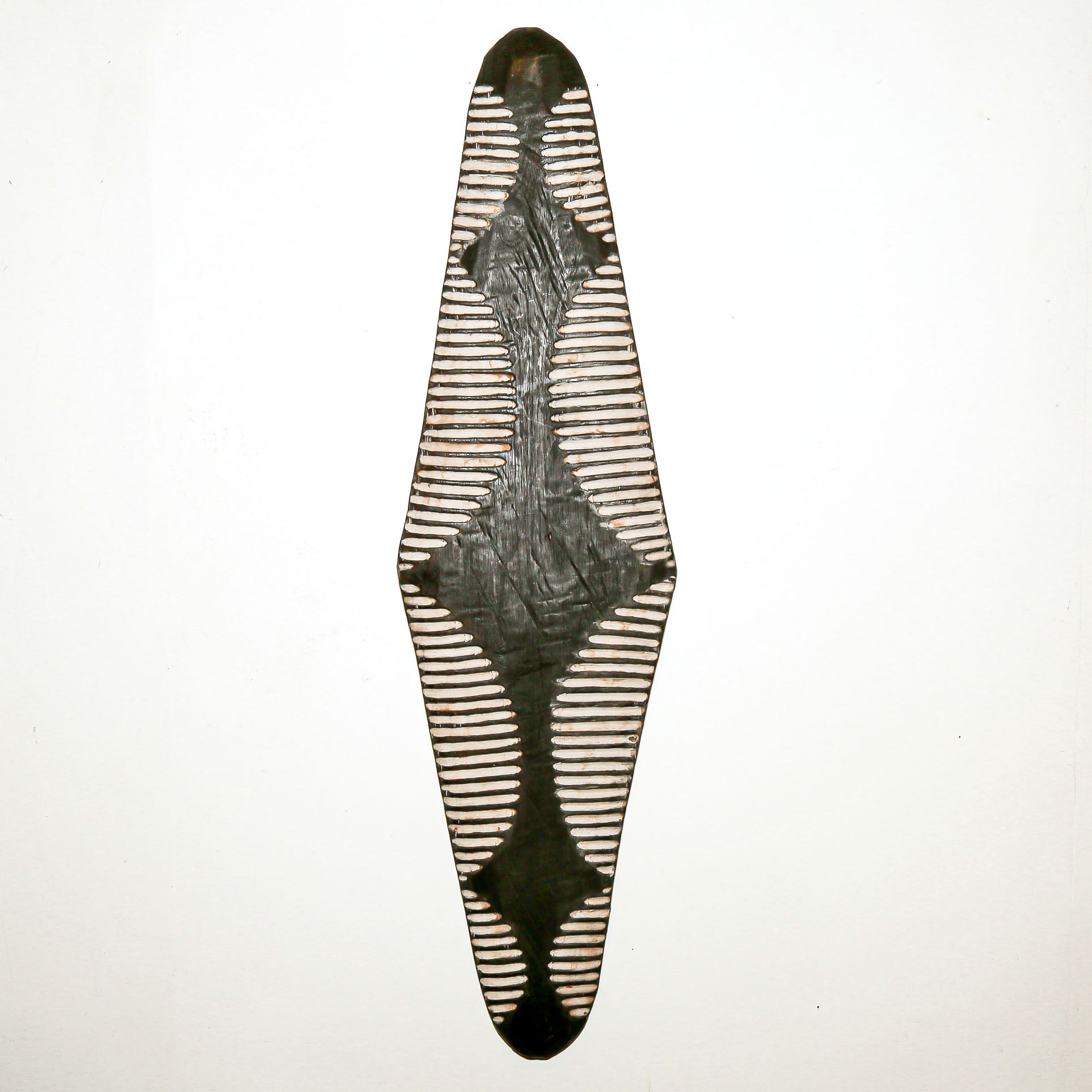 Long wood wall decor with rustic African traditional striped pattern on a white living room wall