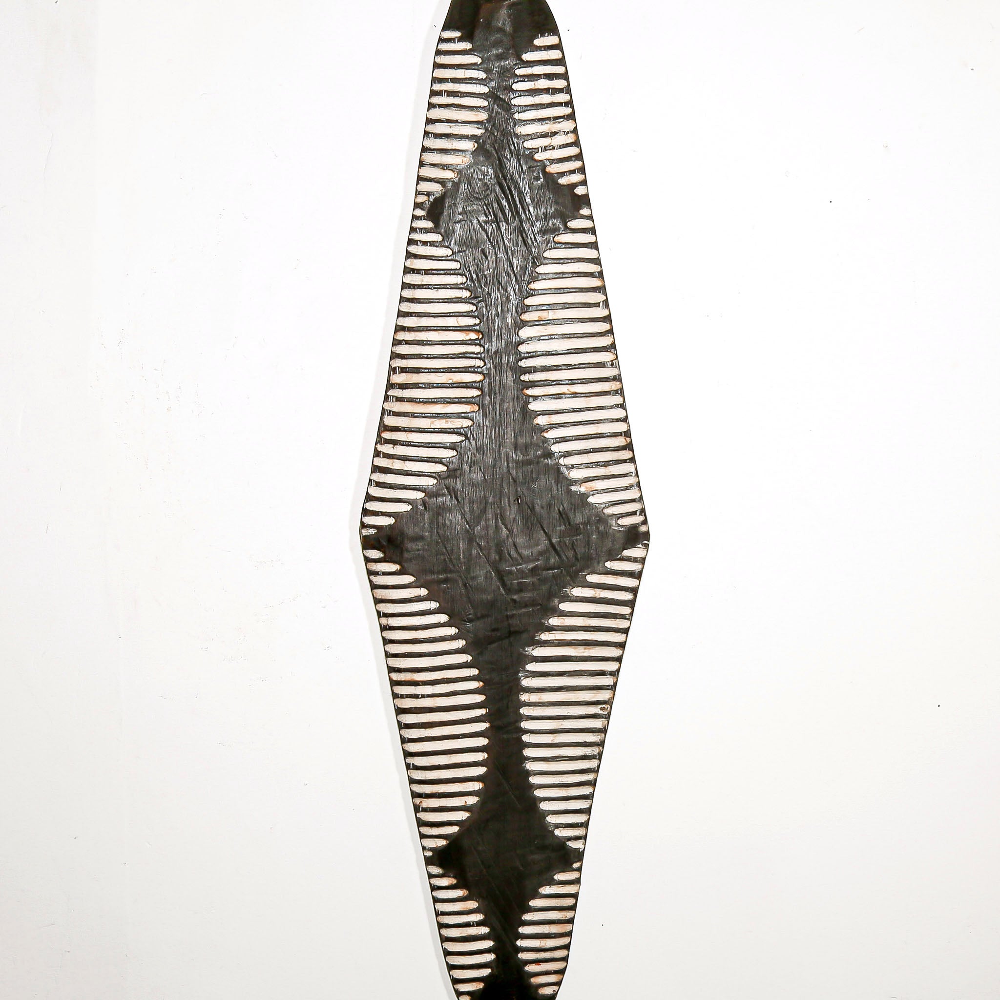 Long wood wall decor with rustic African traditional striped pattern on a white living room wall