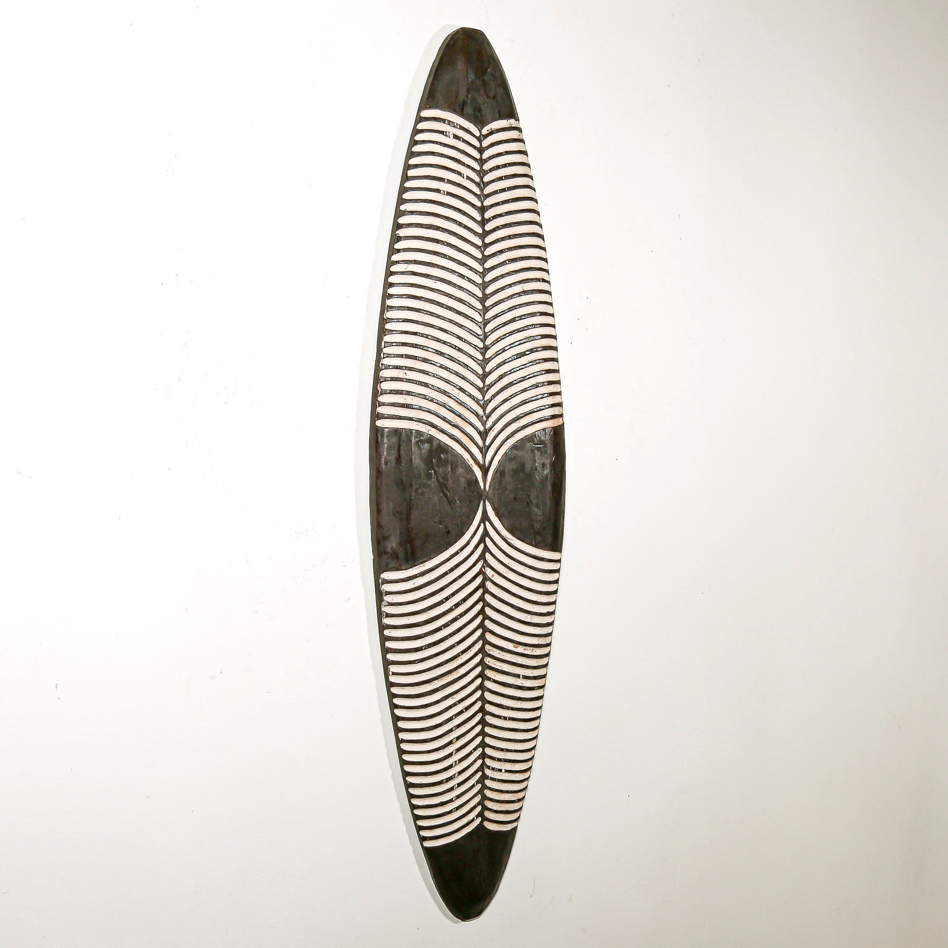 Long wood wall decor with rustic African traditional striped pattern on a white living room wall