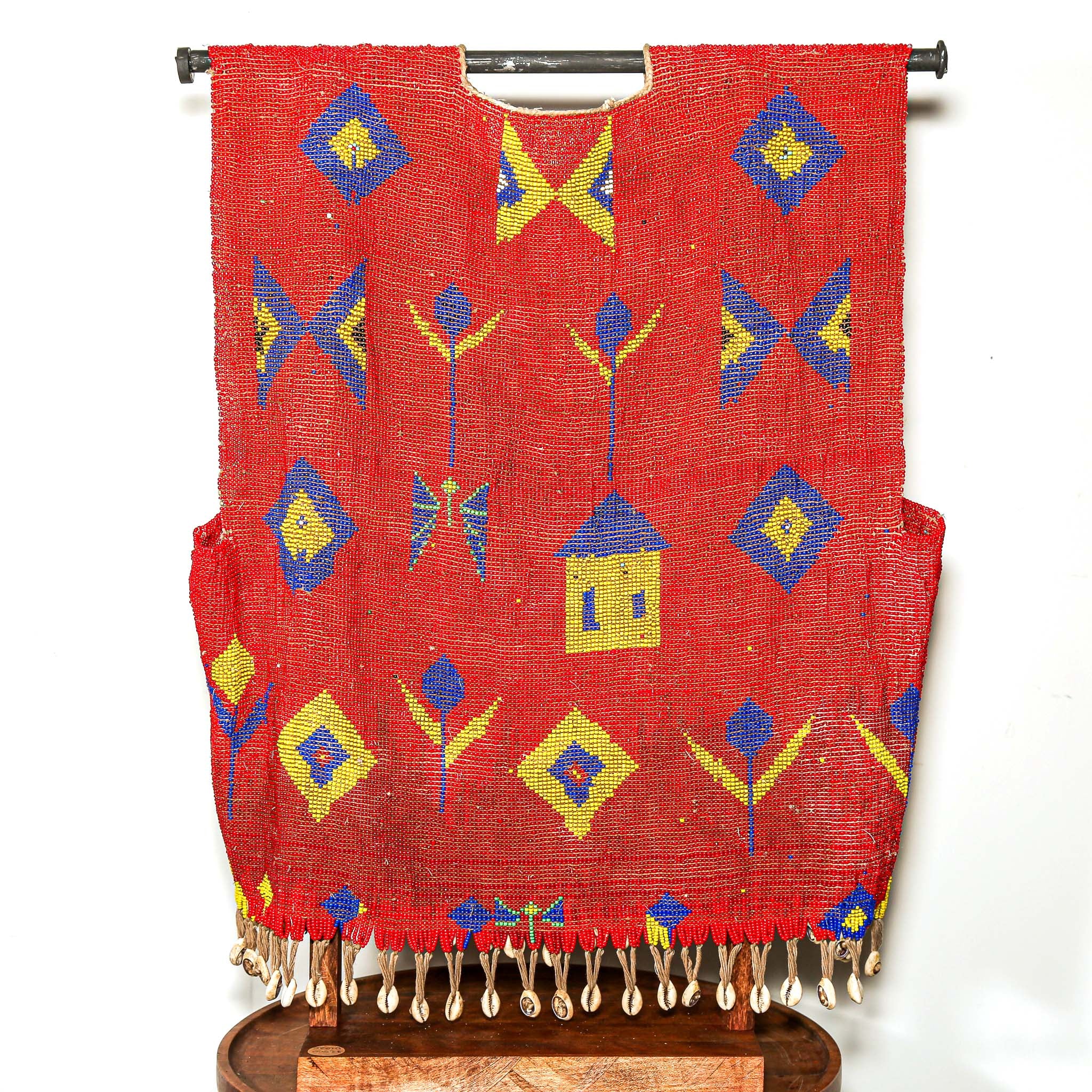 Red beaded garment for sculptural display with geometric patterns on a stand against a white background. high quality collectable African art