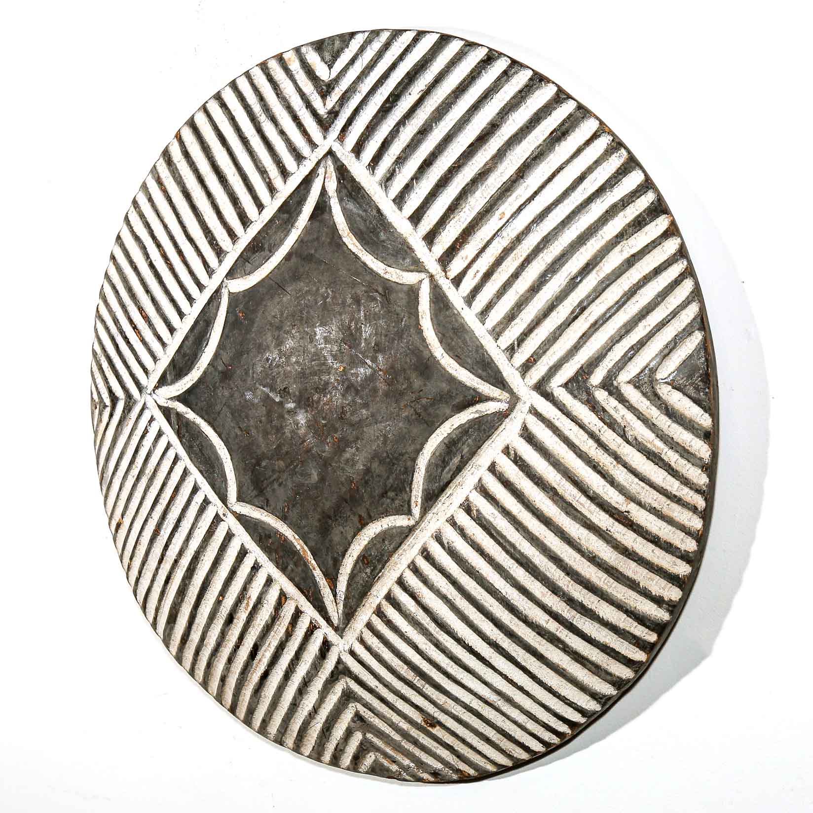 Decorative wall hanging round shield with geometric pattern on a white wall background