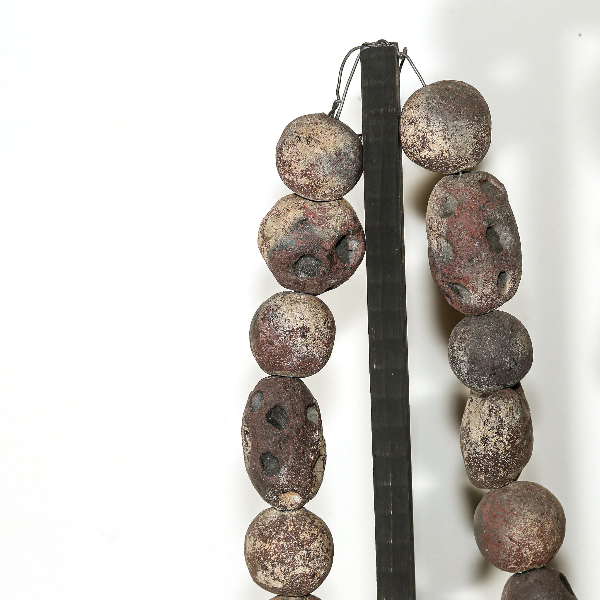 Decorative volcanic rock necklace sculpture with textured stone beads shown as modern sculptural artwork