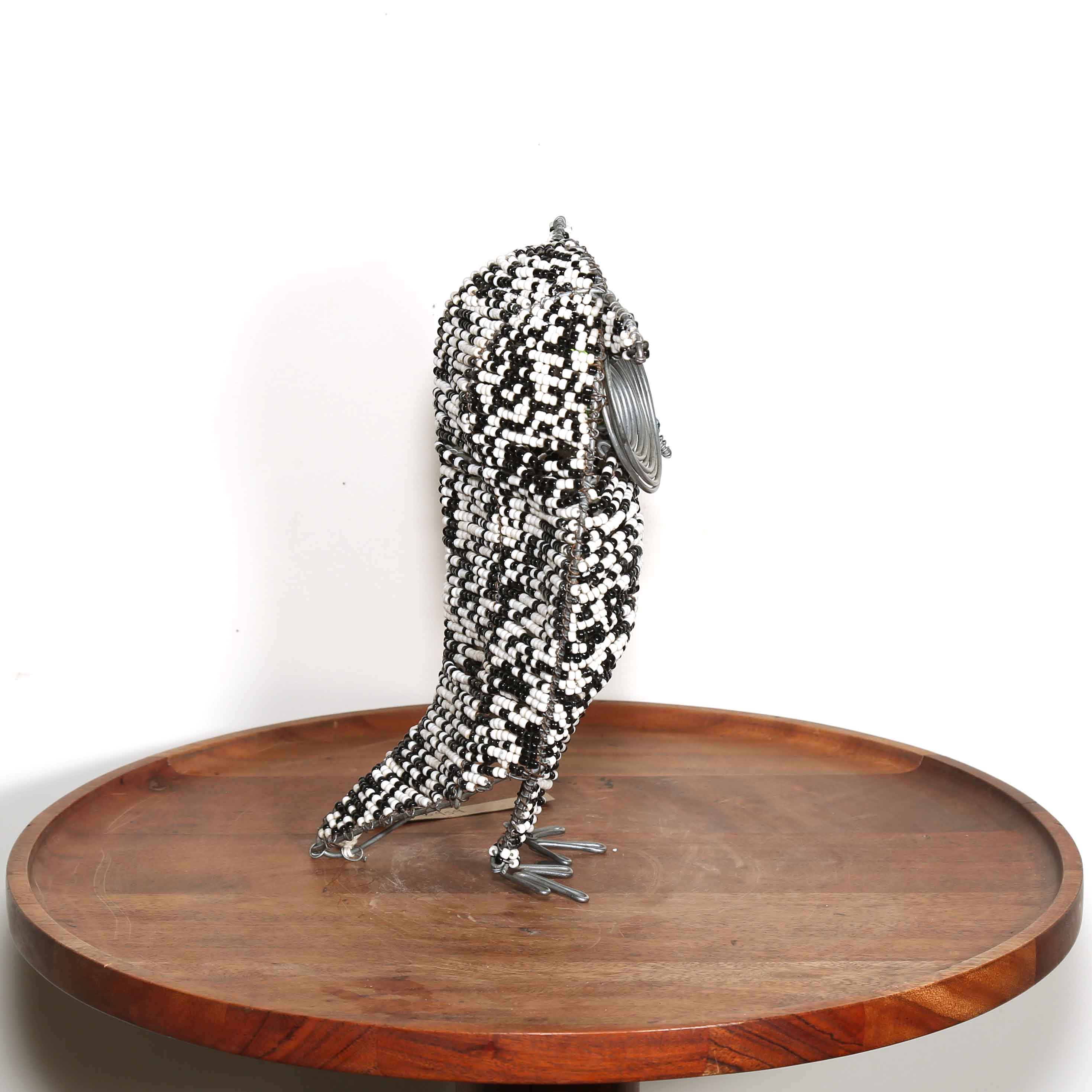 side view of a Metallic and beads owl sculpture on a wooden platform with a white background
