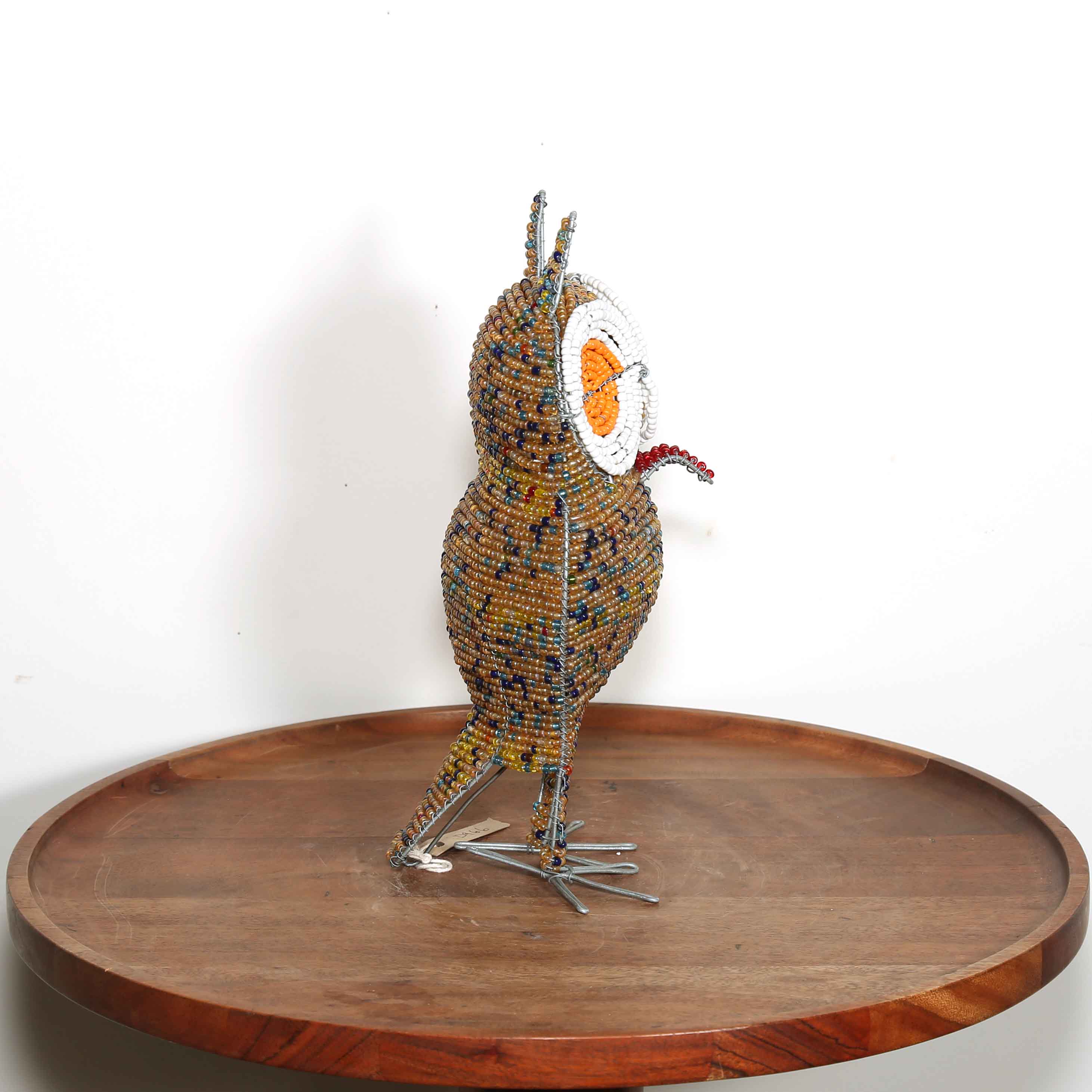 speckled gold African owl artwork with white and orange eyes view from the side