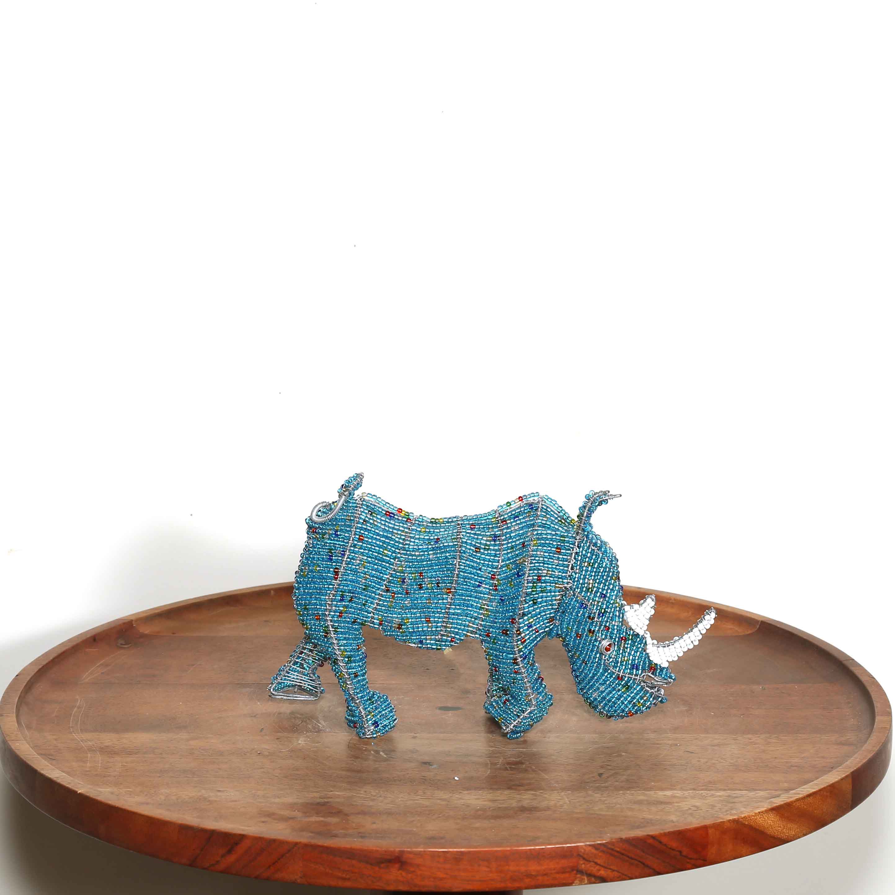 Blue beaded rhinoceros on a wooden tray with a white background