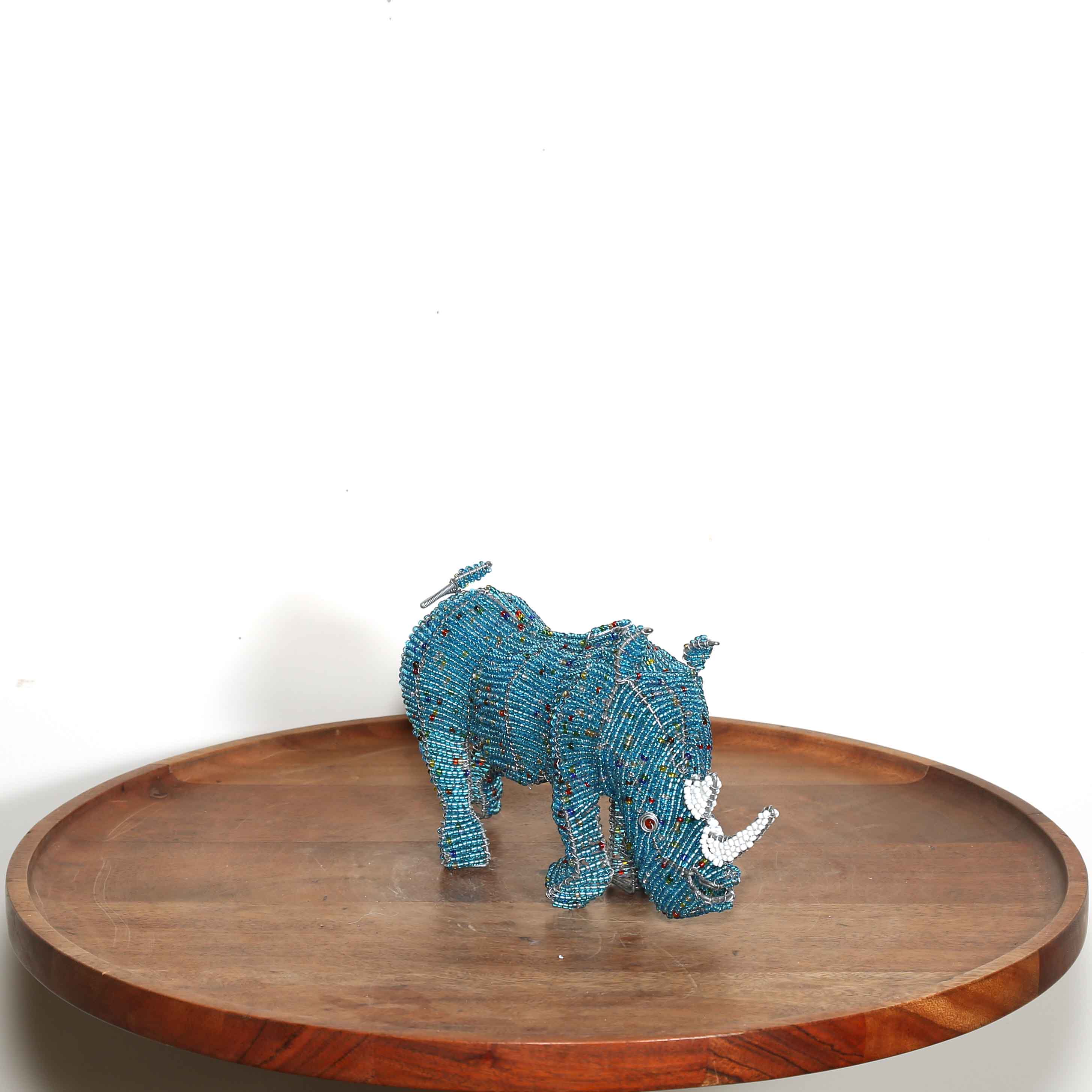 Blue beaded rhinoceros on a wooden tray with a white background