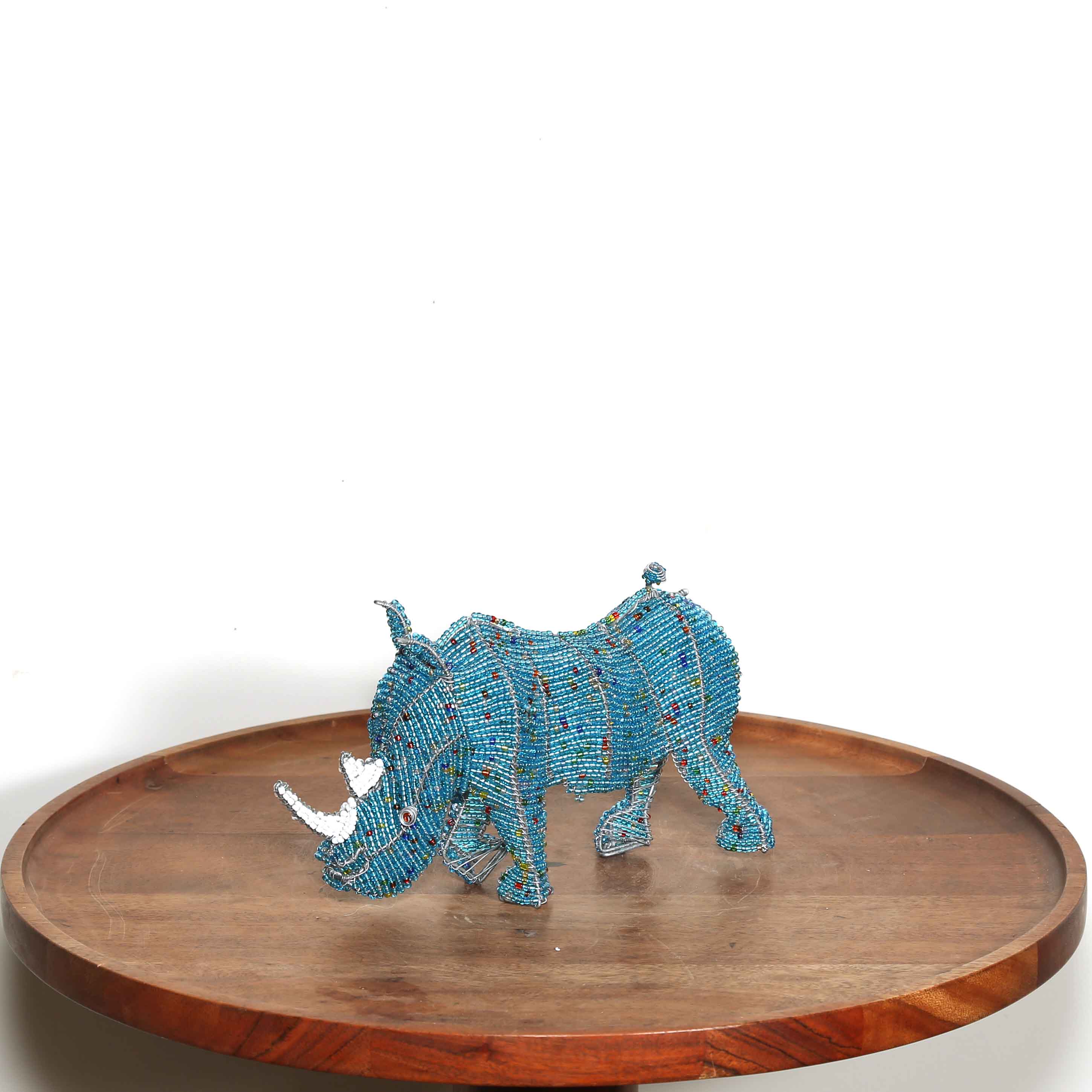 Blue beaded rhinoceros on a wooden tray with a white background