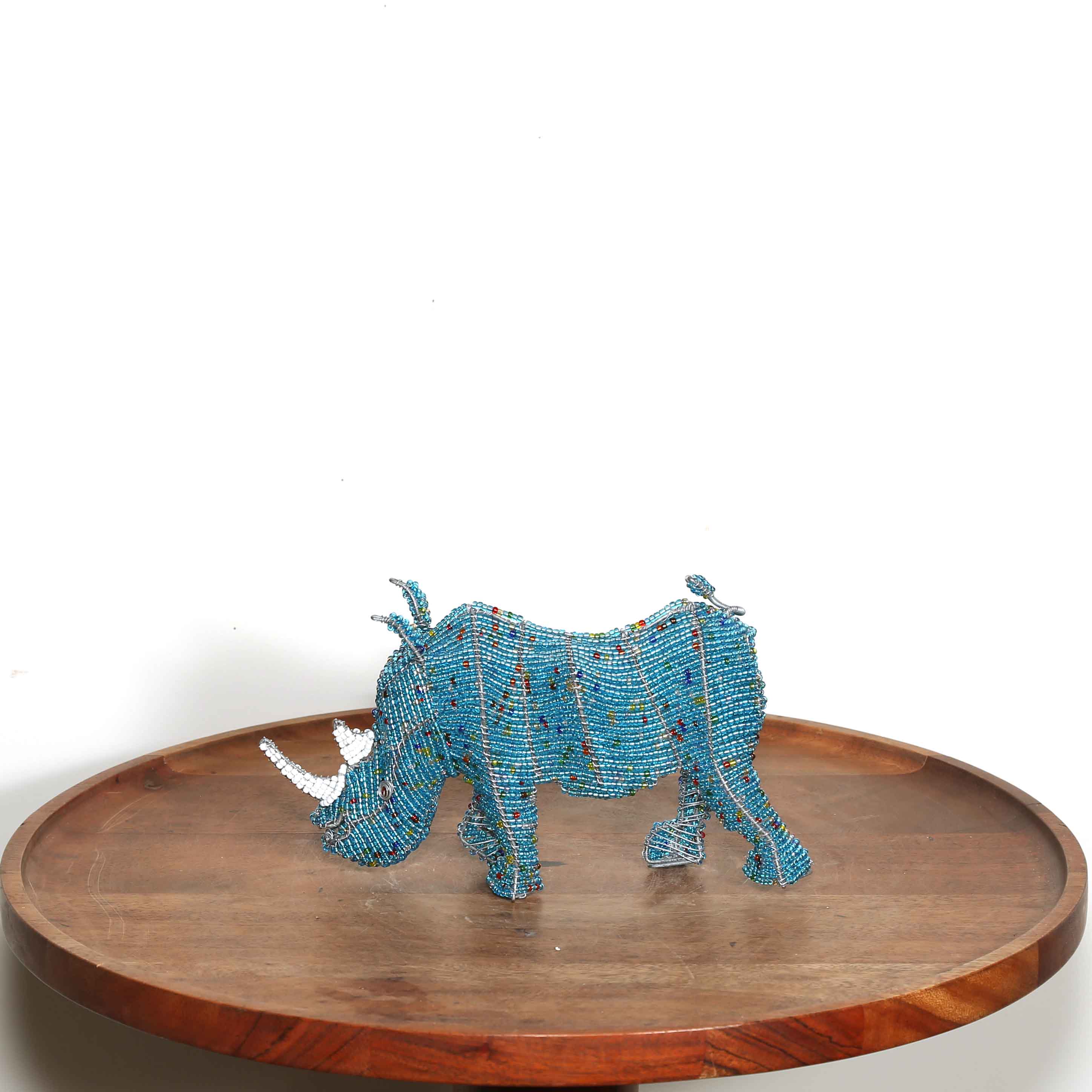 Blue beaded rhinoceros on a wooden tray with a white background
