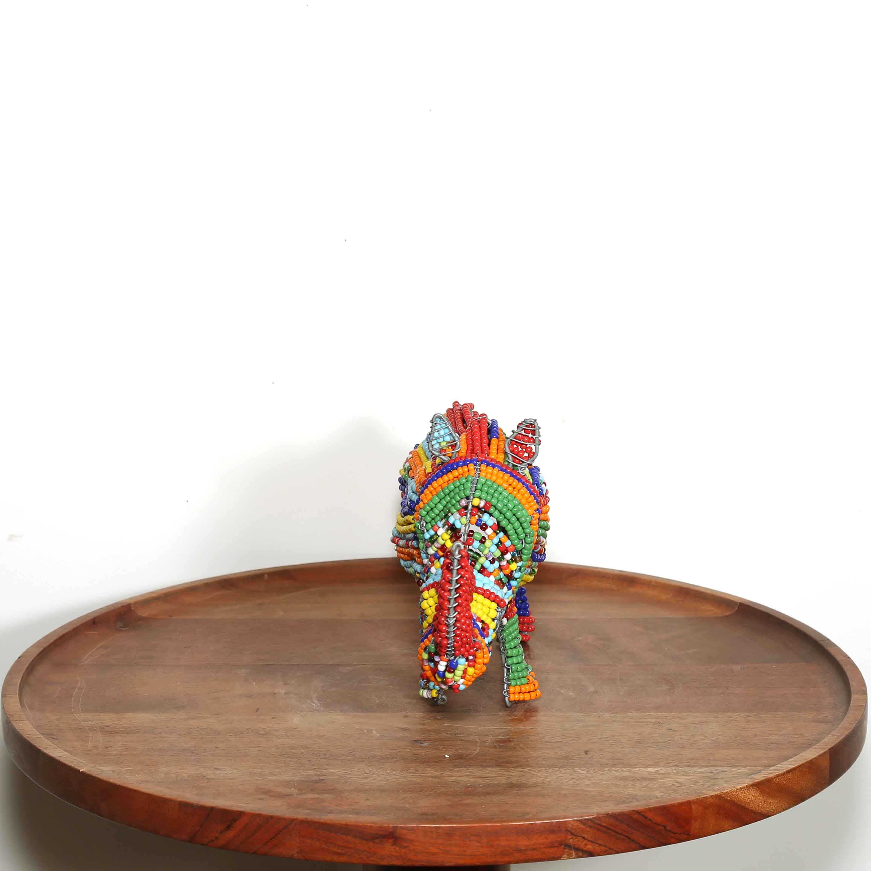 Colorful beaded rhino on a wooden tray with a white background