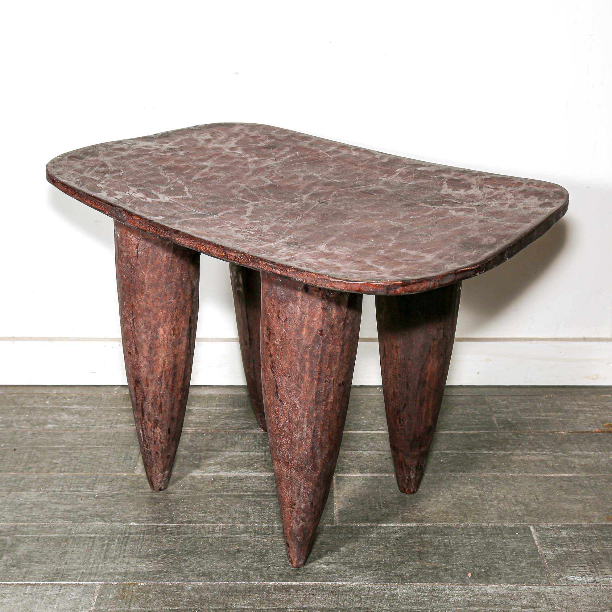 square African wood table with four pointed legs on a wooden floor