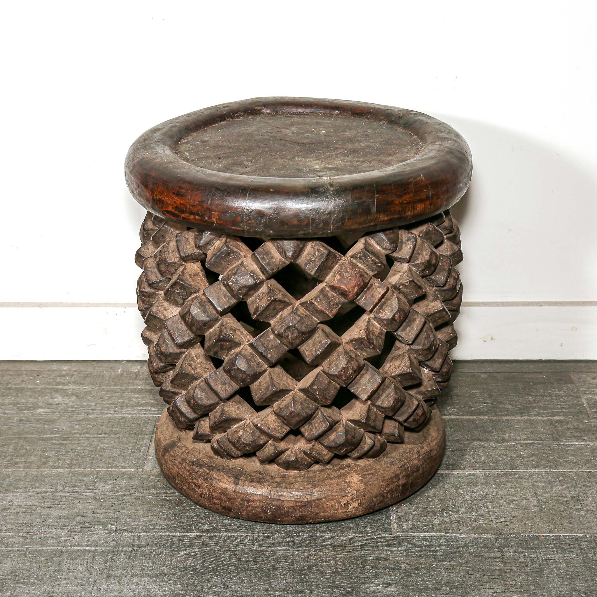 round vintage stool from Africa with a carved woven design on a living room floor