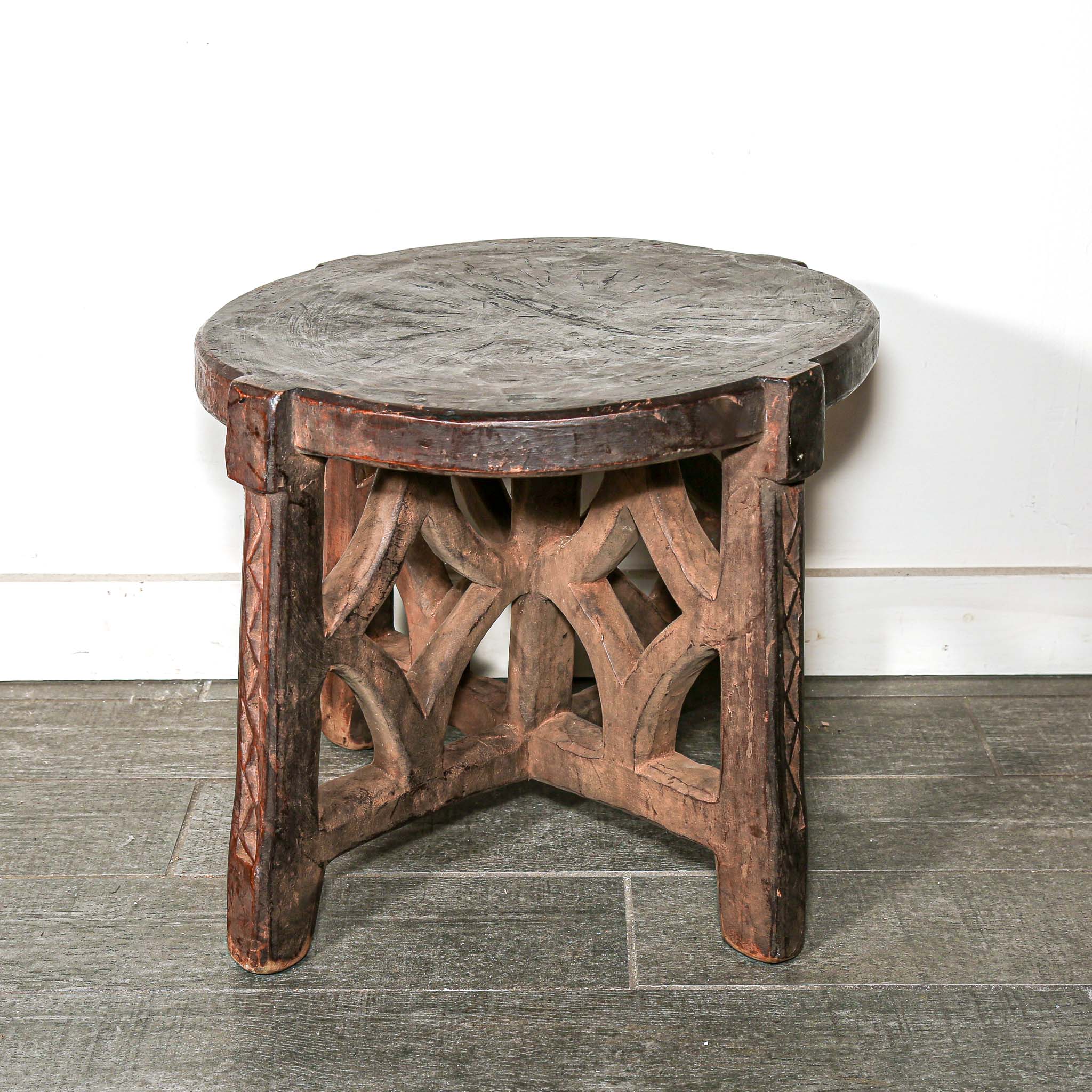 rustic African Round wooden table with a handmade feel on a bedroom floor