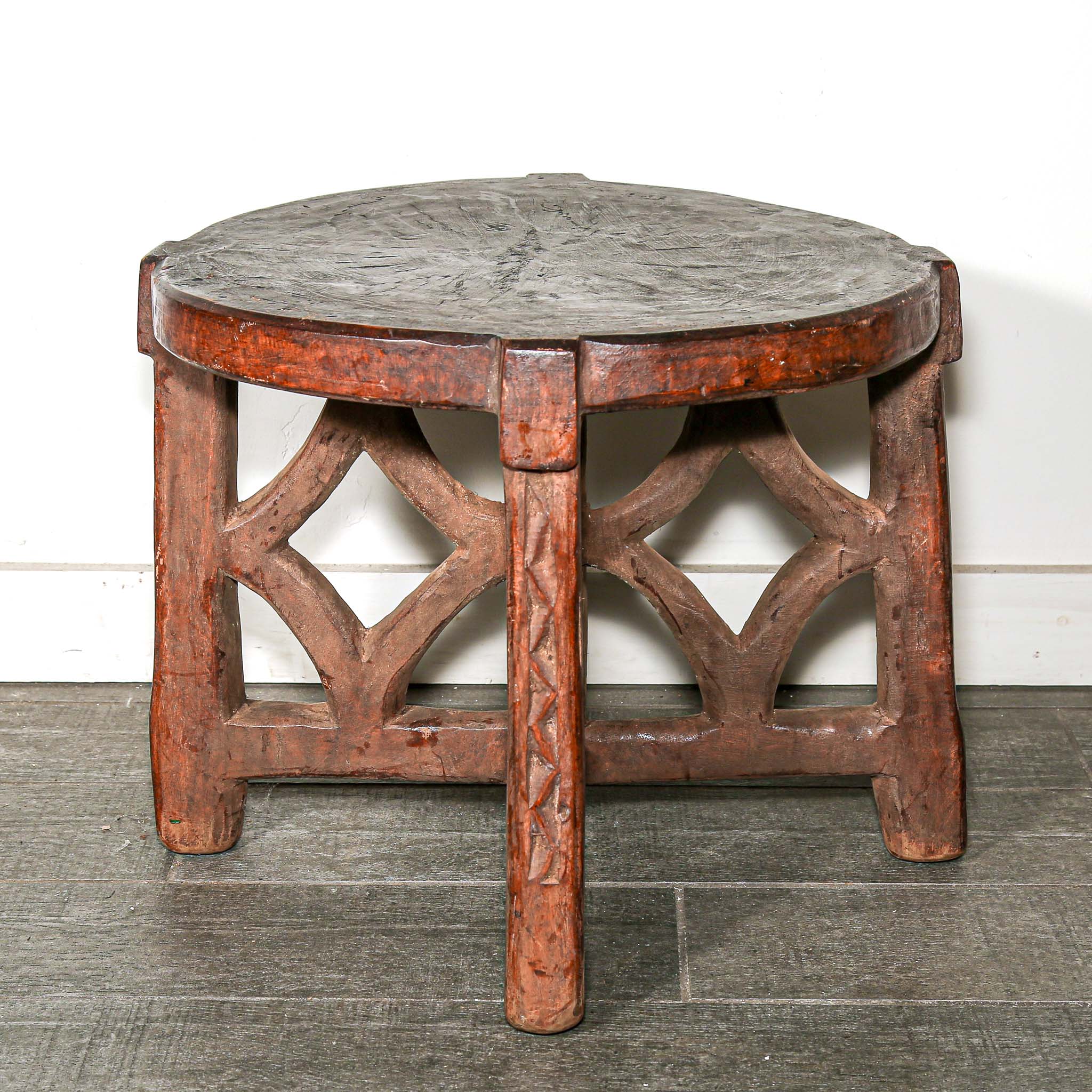 rustic African Round wooden table with a handmade feel on a bedroom floor