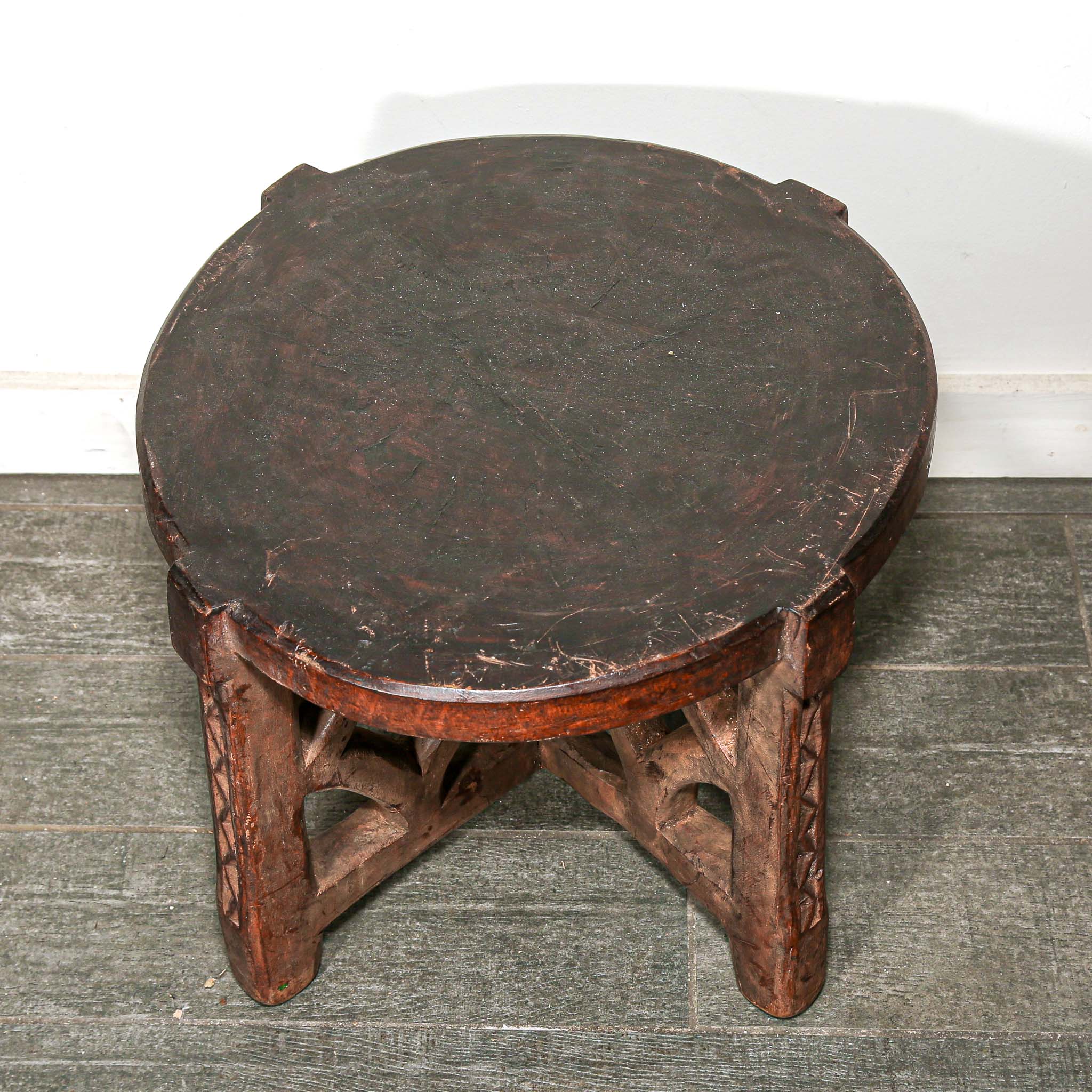 rustic African Round wooden table with a handmade feel on a bedroom floor