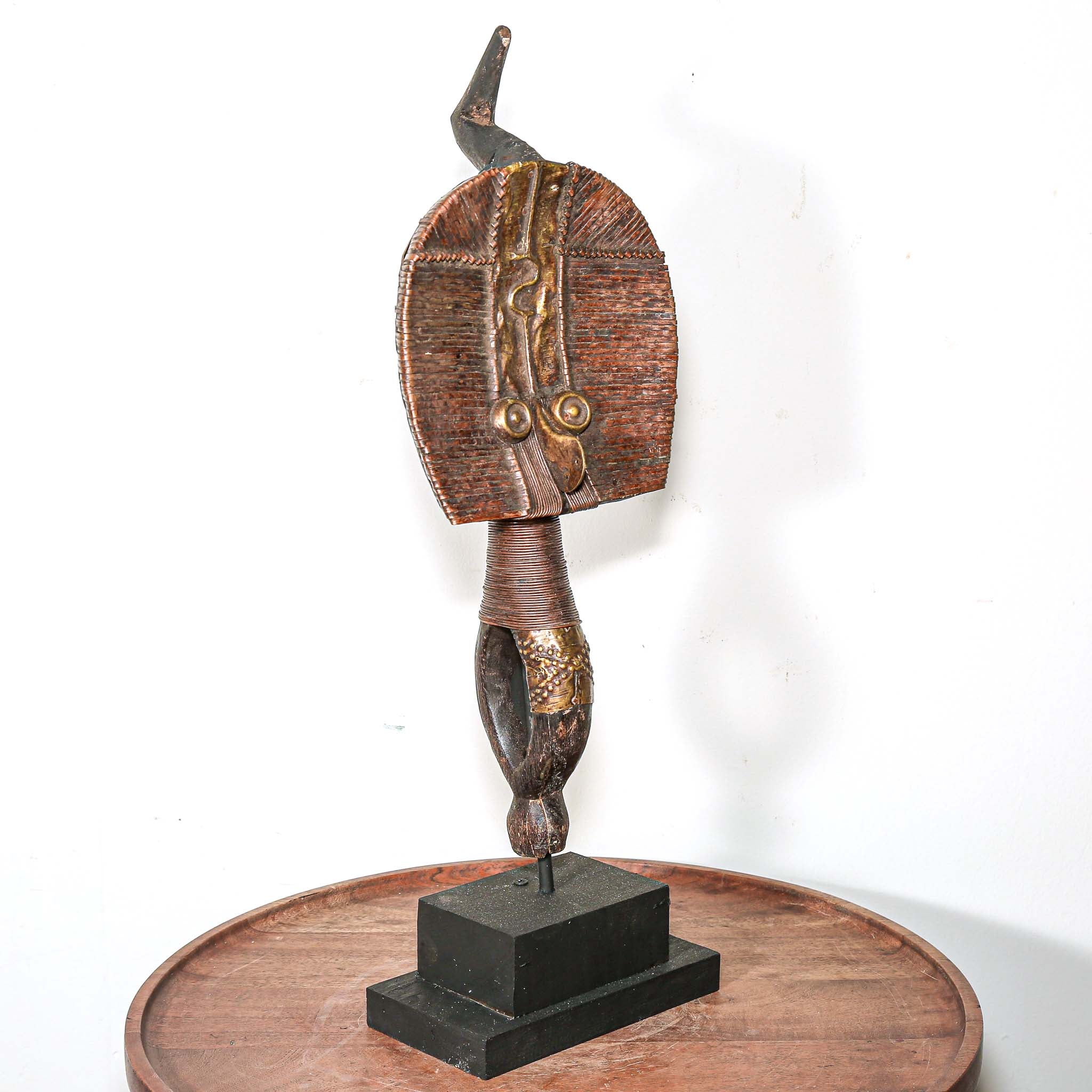 Decorative vintage African art on a stand with a white background