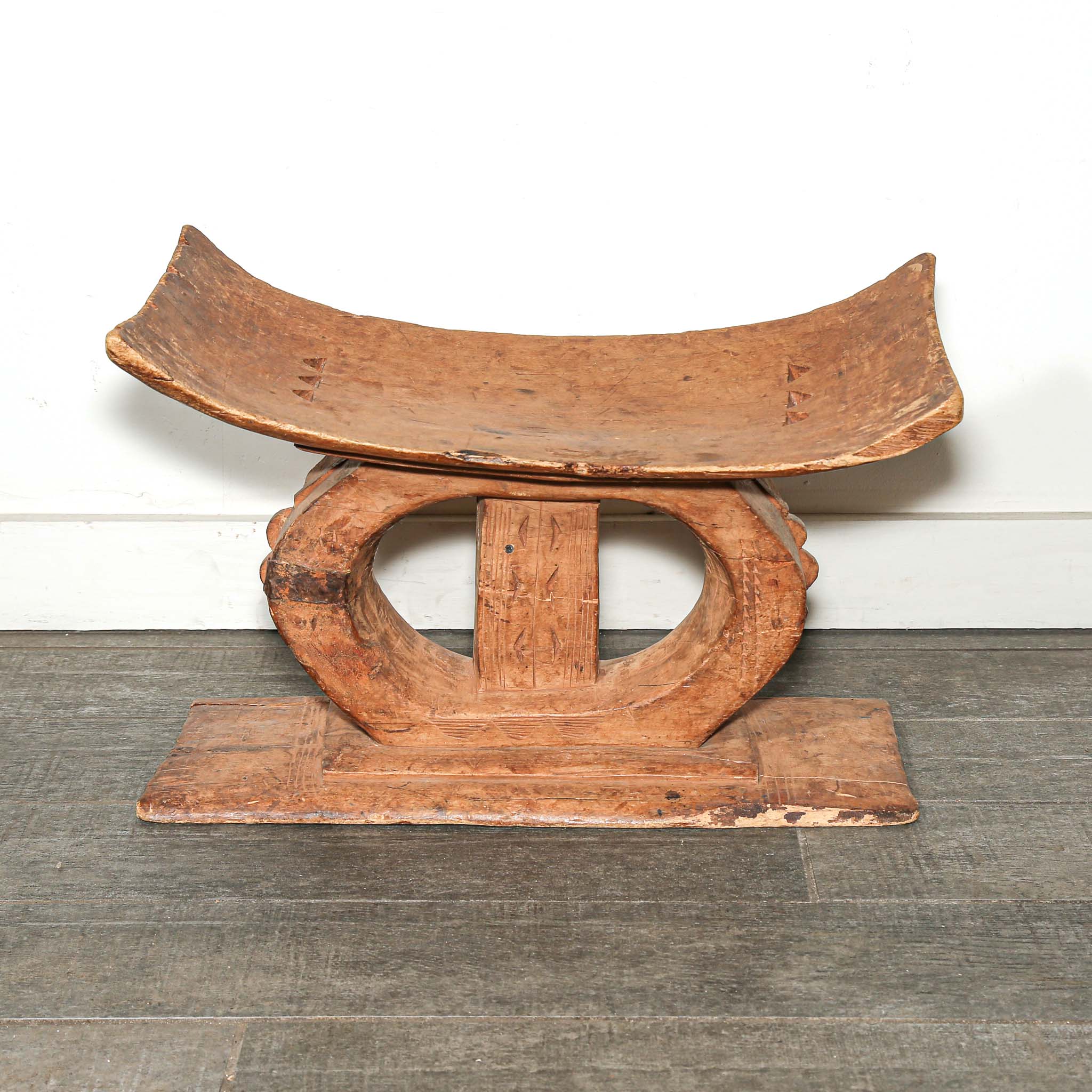 Wooden African table stool with curved top and base on a wooden floor used as bedroom African furniture