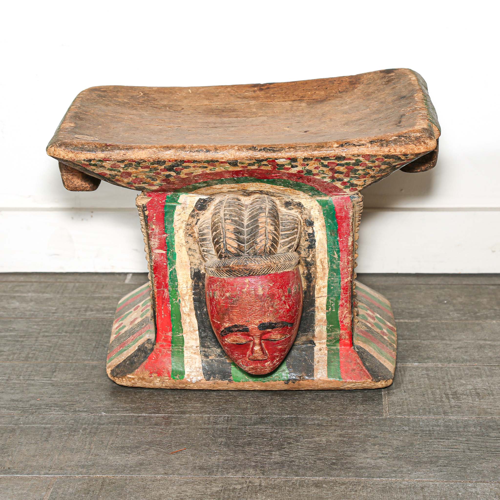 Vintage Wooden African stool with a red face design on a white background