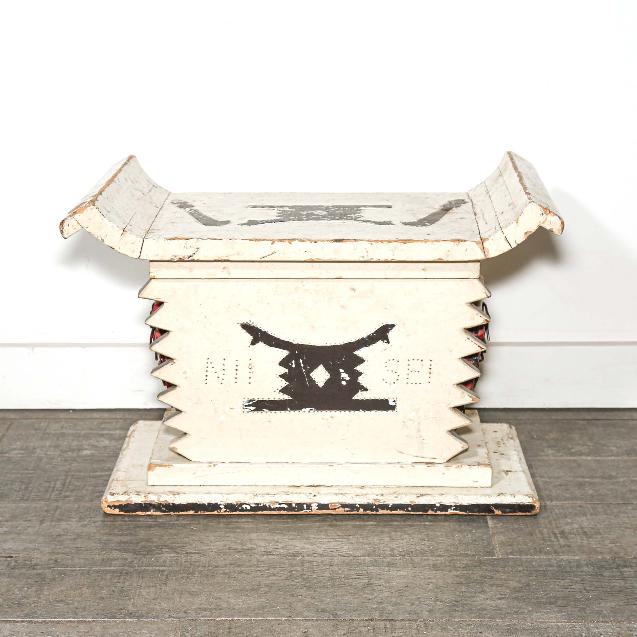 White wooden African stool furniture with cabinet and black distressed accents on a wooden living room floor