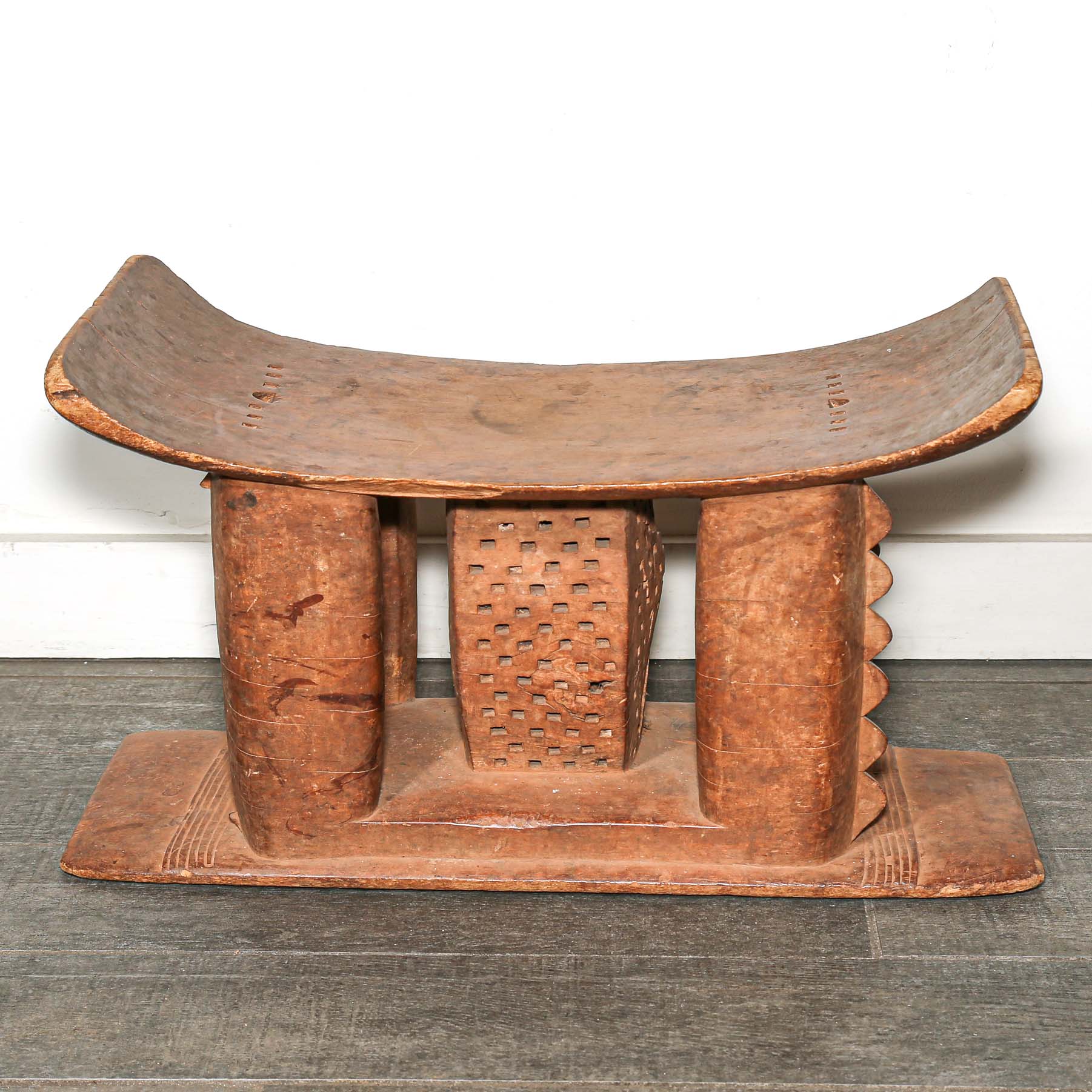 Wooden African vintage furniture with a curved backrest on a bedroom floor.