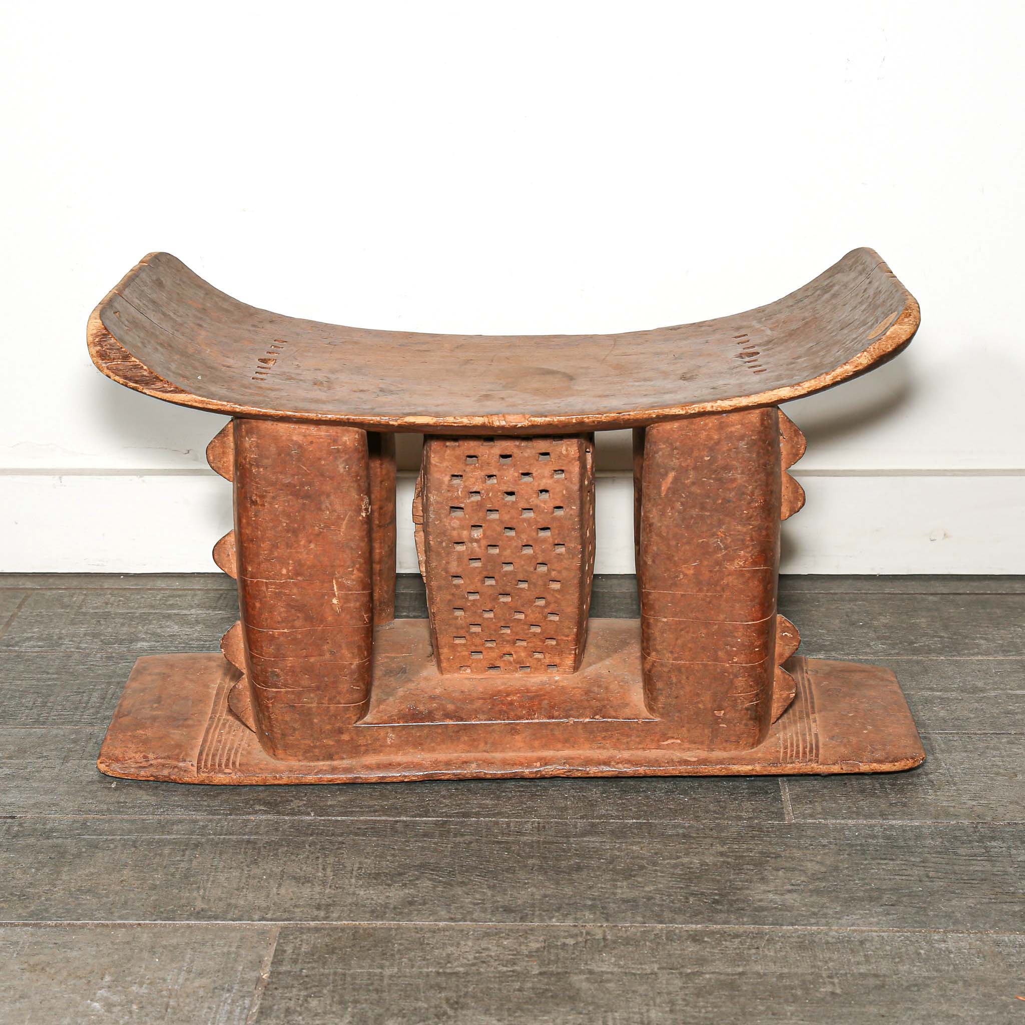 Wooden African vintage furniture with a curved backrest on a bedroom floor.