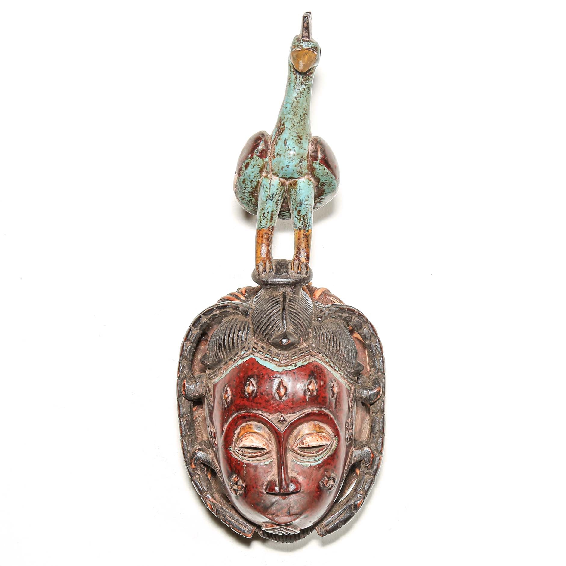 Guro African mask with colorful bird headdress. Red blue brown and black colors hanging on the wall