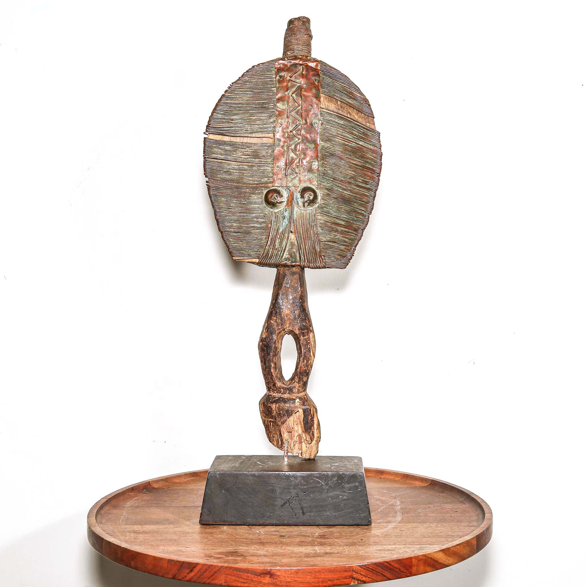 Wooden protective traditional mask on a round wooden table with a white background
