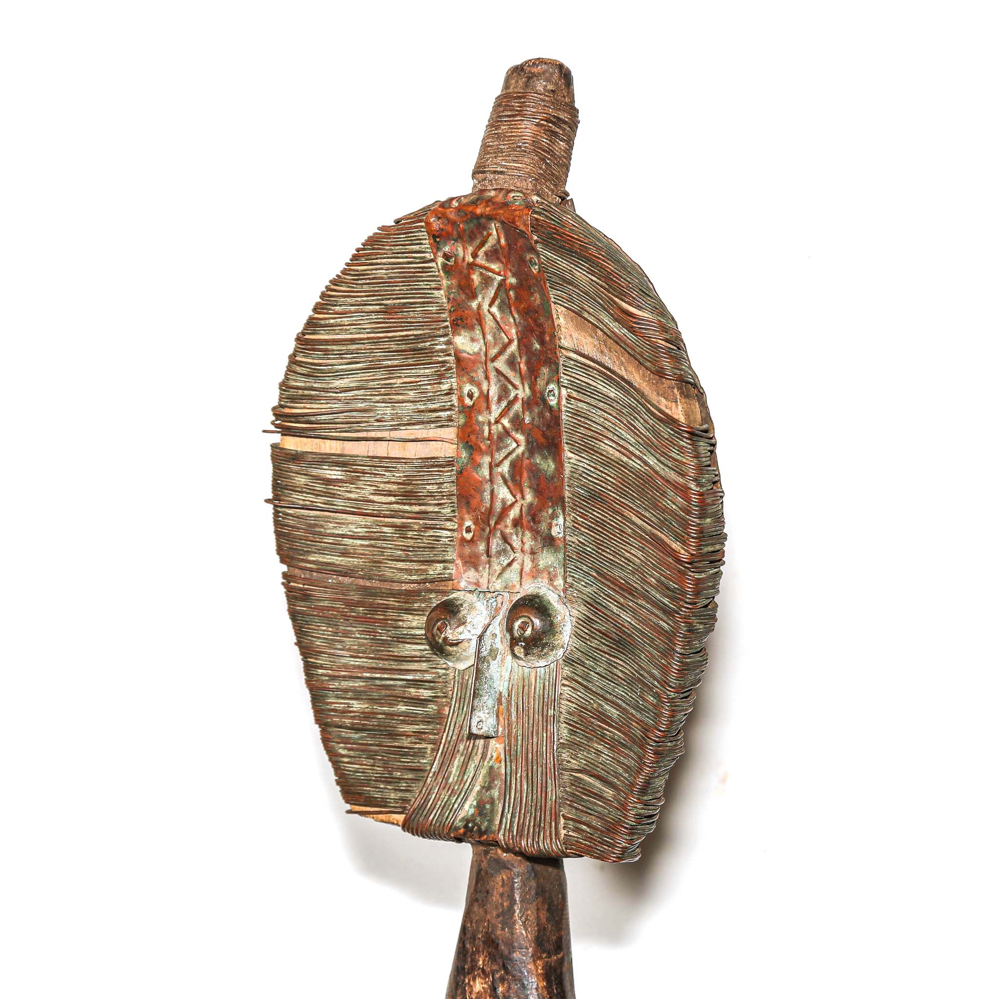 Wooden protective traditional mask from Gabon made from wood and metal on a round wooden table with a white background close up from the side
