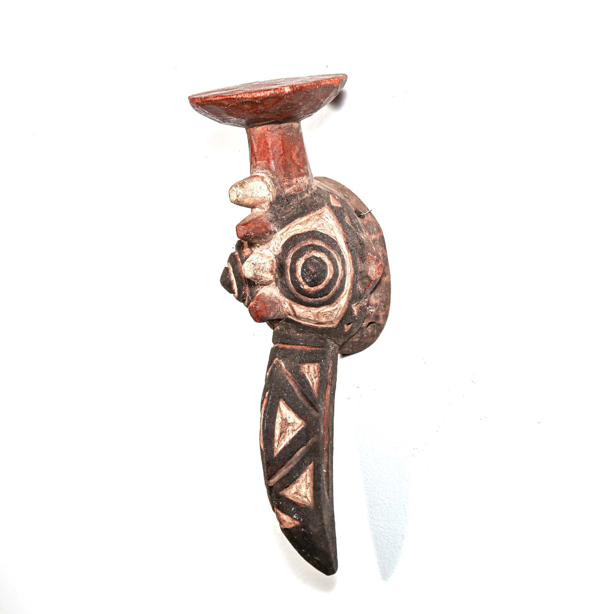hand made carved wood bird-shaped mask with intricate designs on a white background
