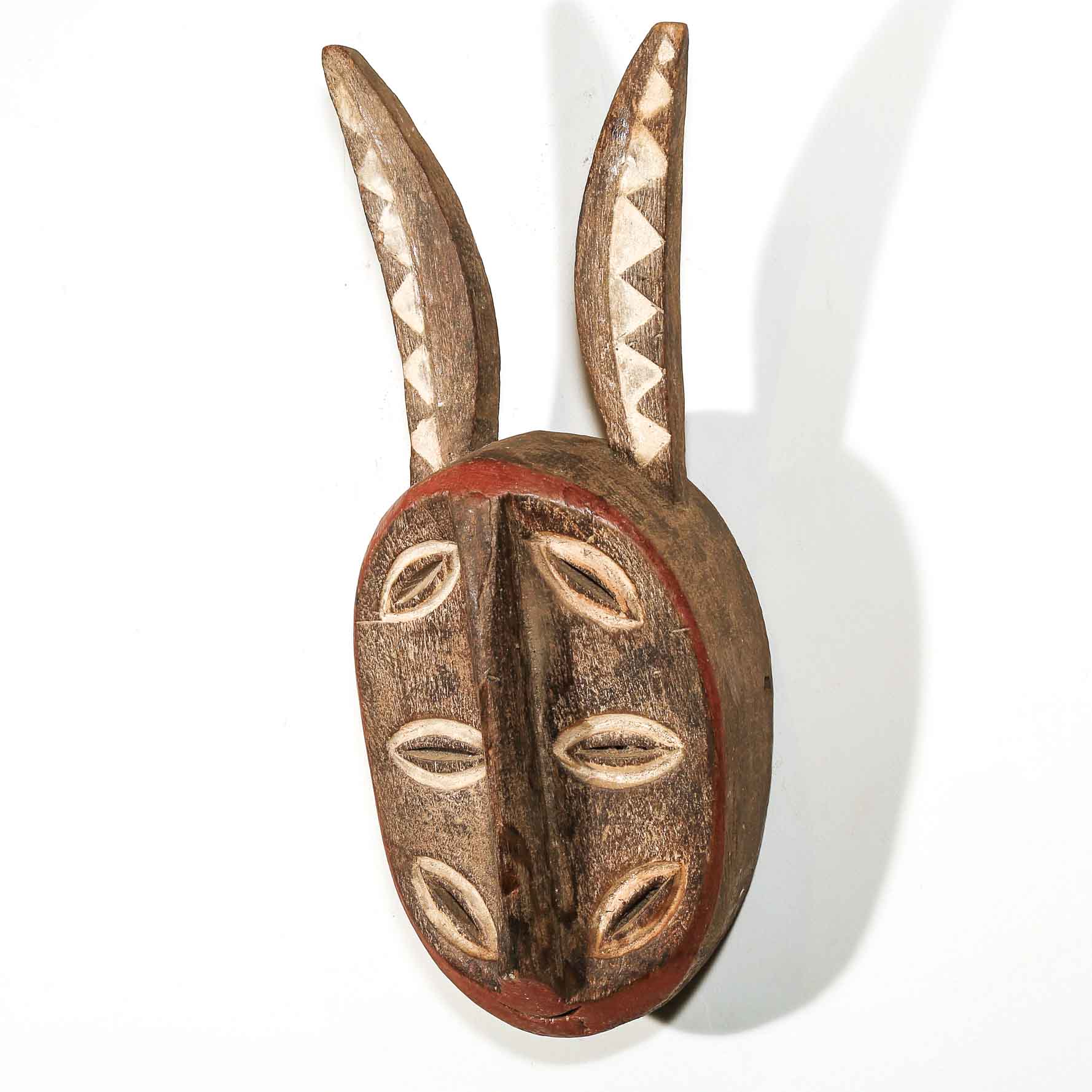 Wooden brown African mask with antelope horns on a white background