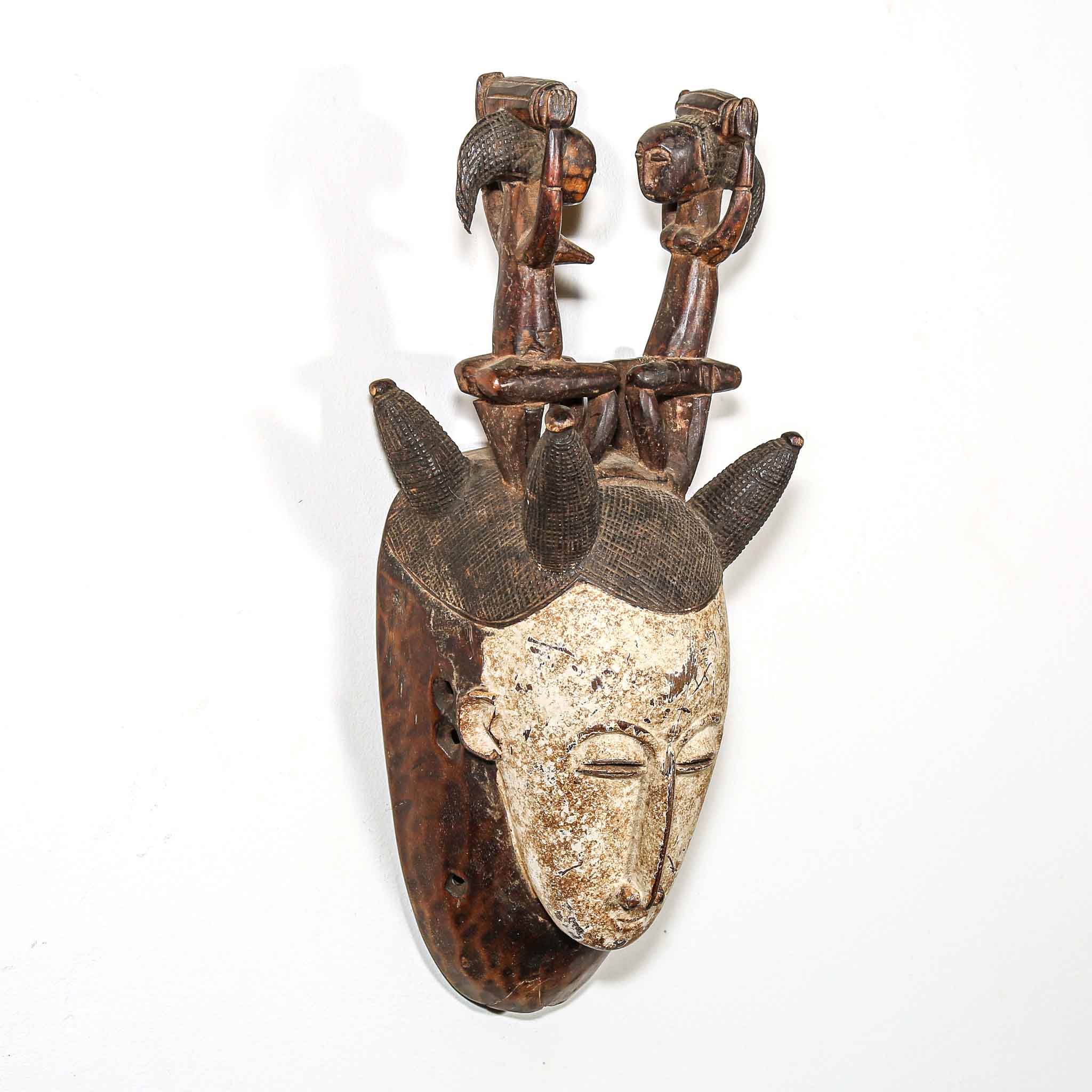 Wooden mask with a face and additional elements on a white background