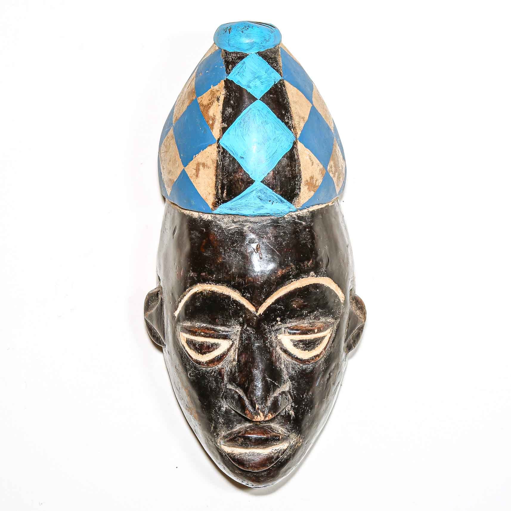 African mask with a blue and white headdress on a white background with a dark face