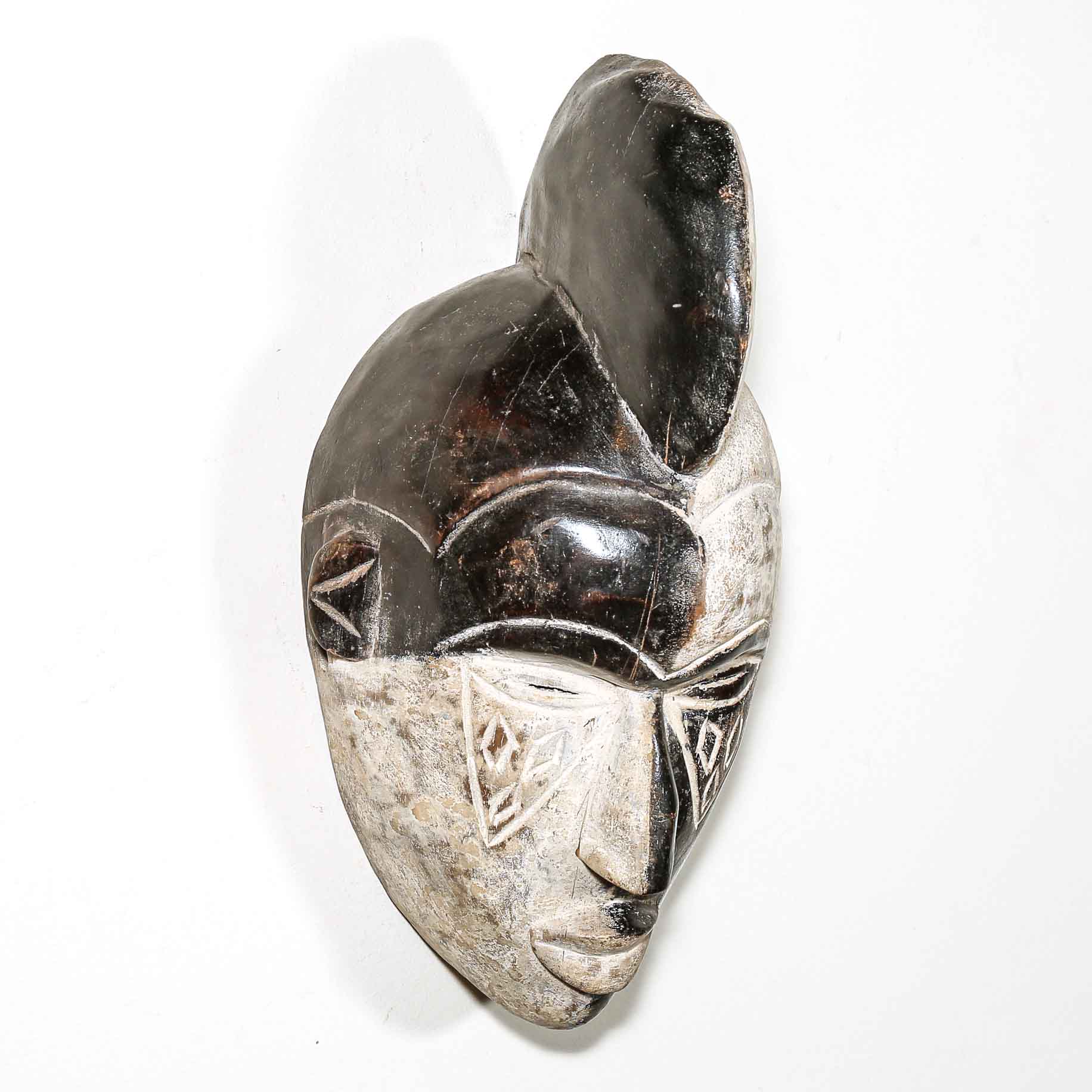 Carved wood mask with intricate designs on a white background