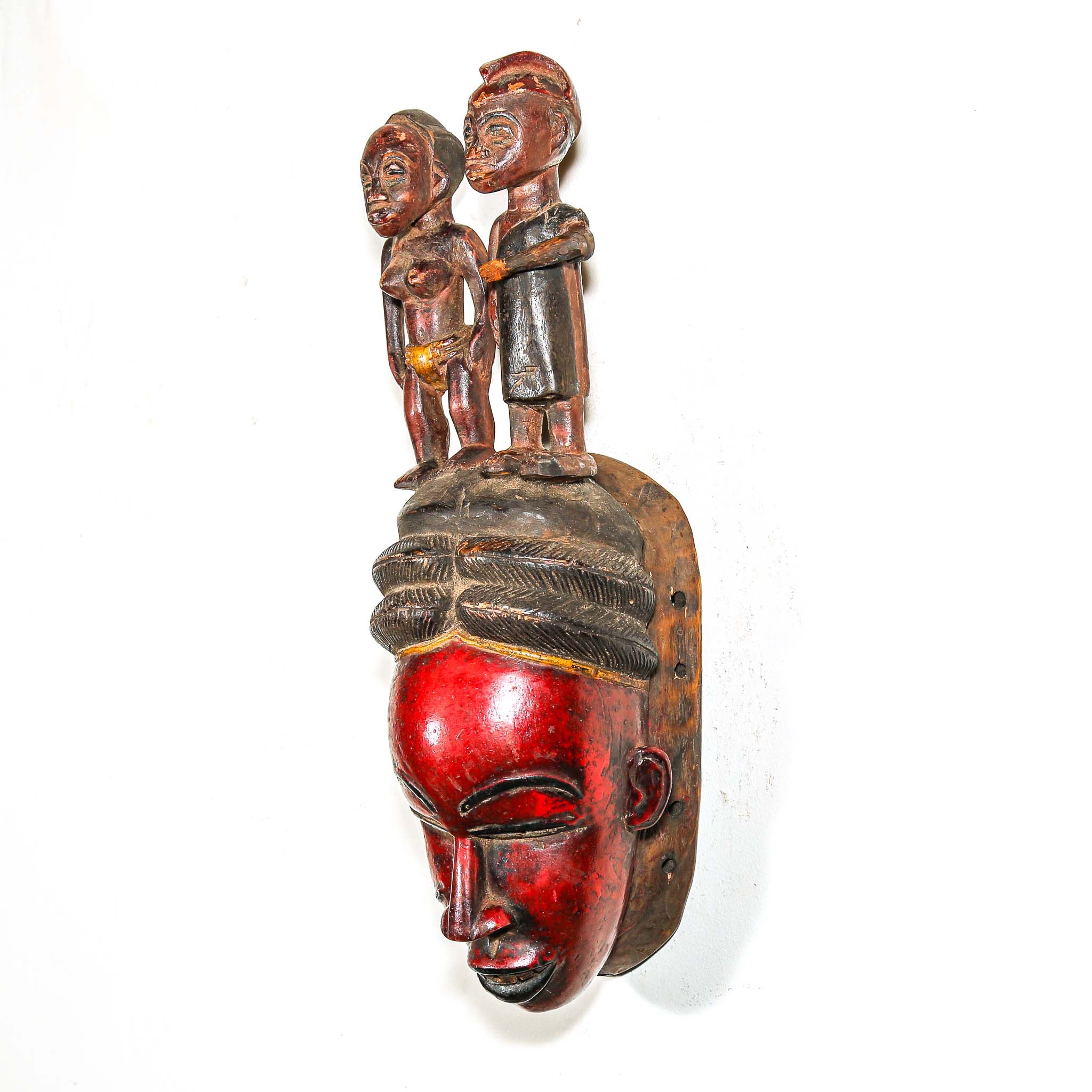 Carved wooden mask with two figures on a white background