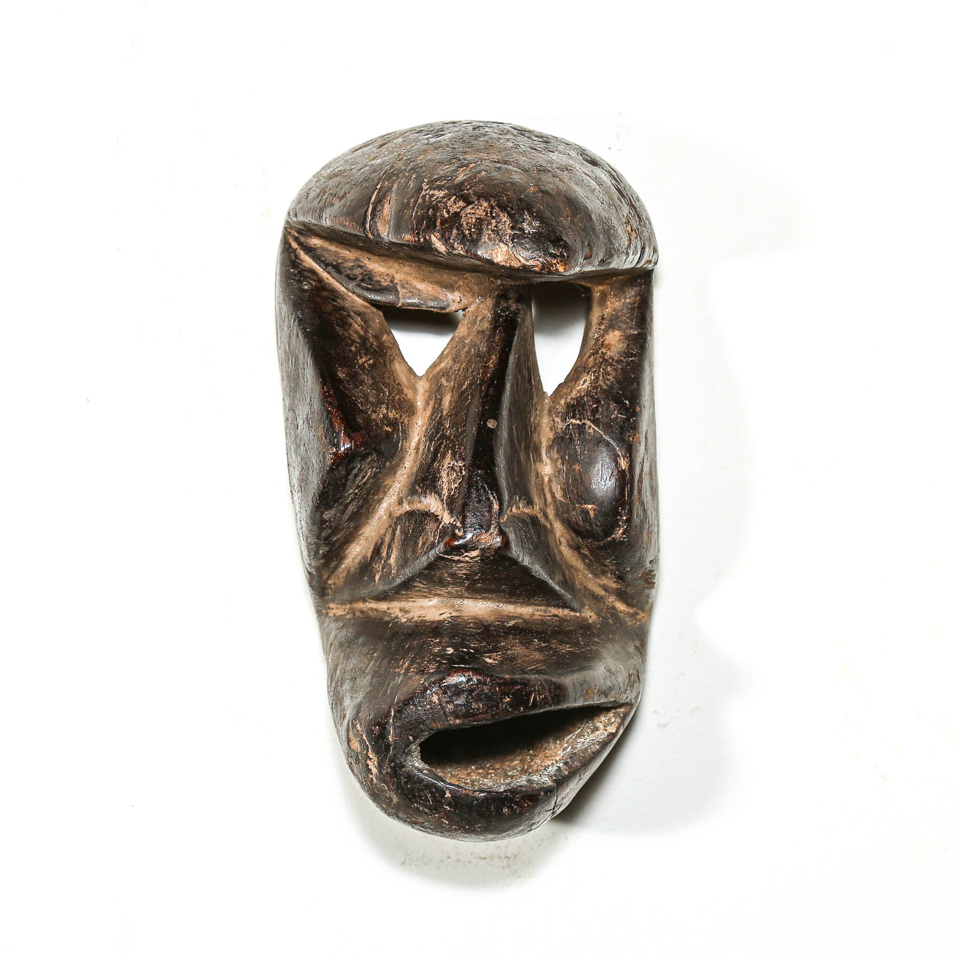 Carved antique tribal ceremonial black wooden mask on a white background