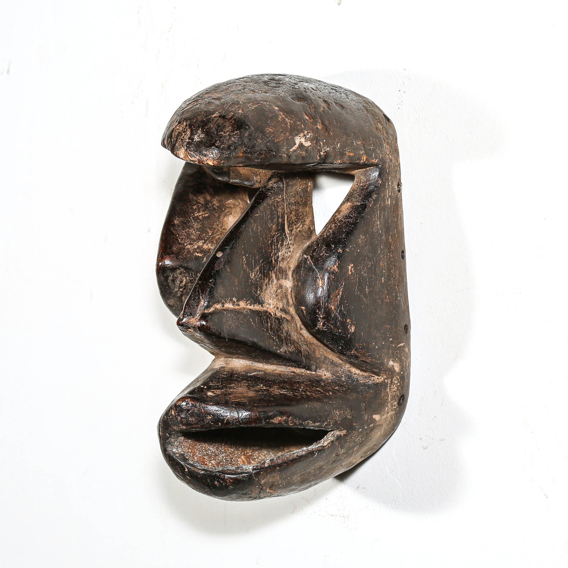 Carved antique tribal ceremonial black wooden mask on a white background