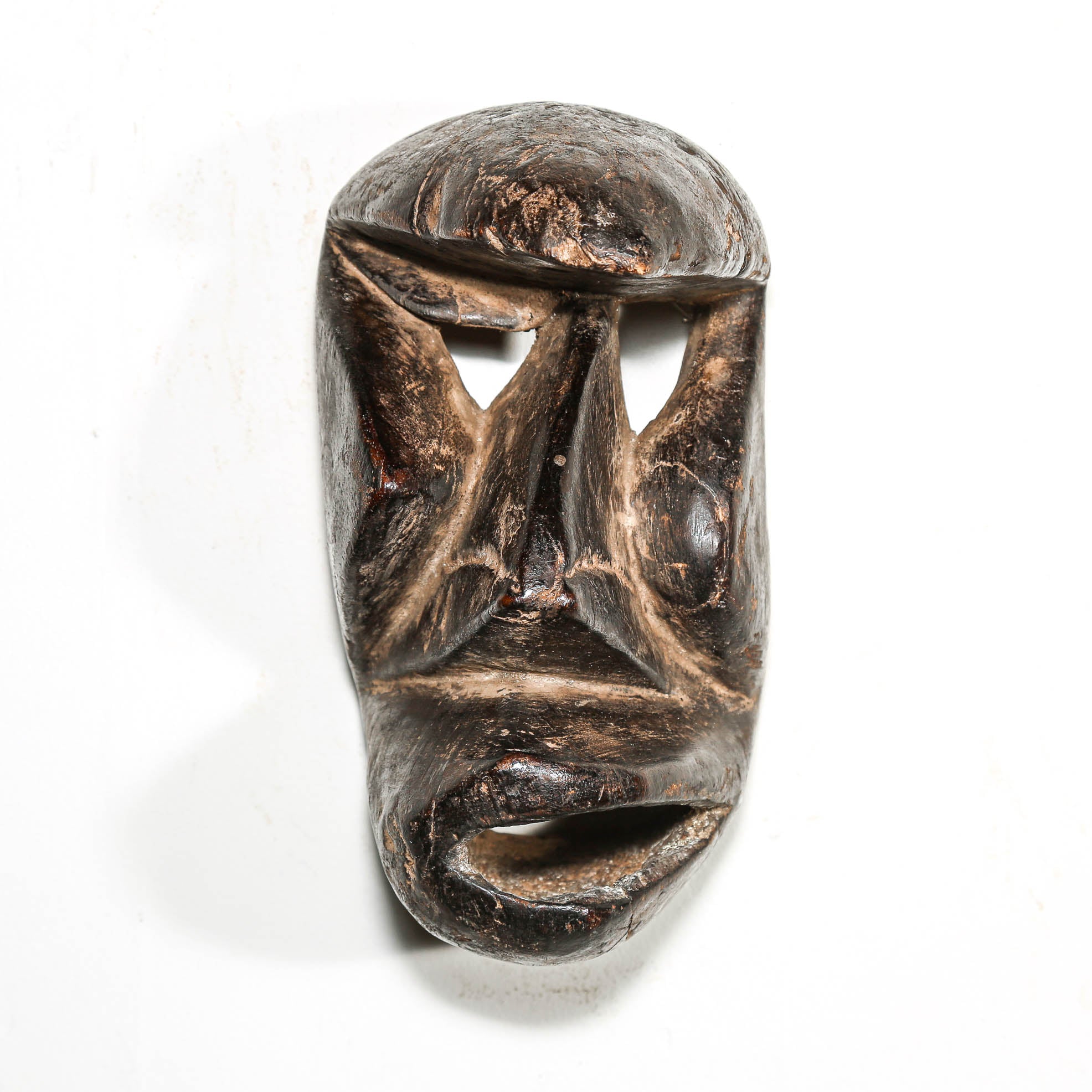 Carved antique tribal ceremonial black wooden mask on a white background