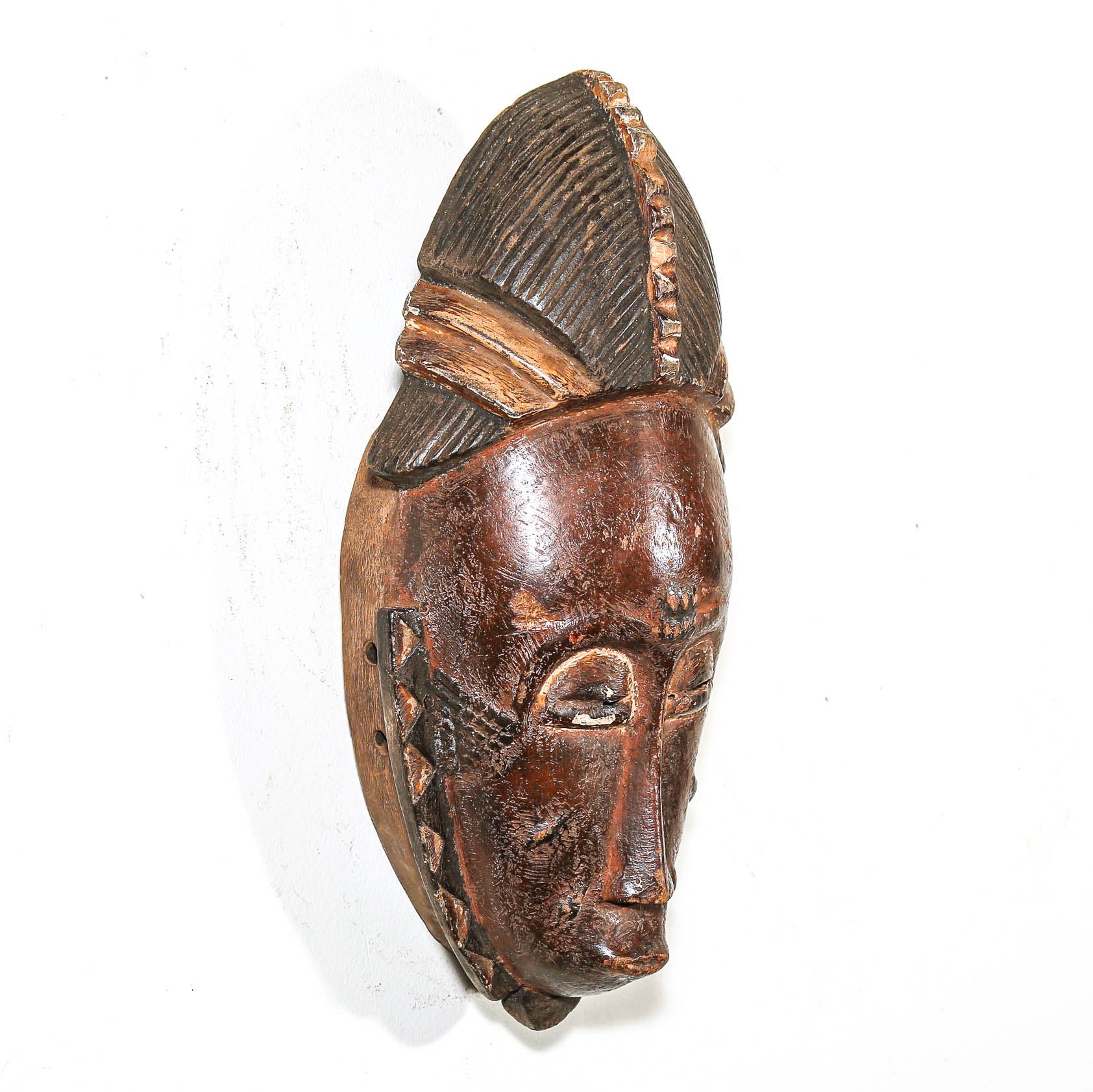 Wooden mask with intricate carvings on a white background
