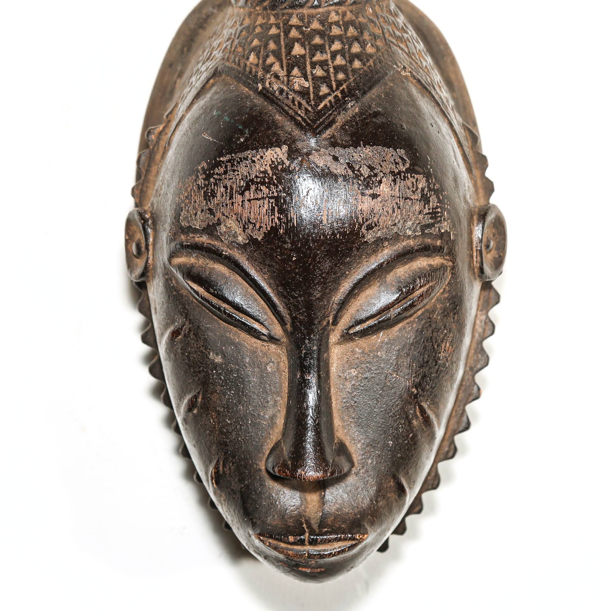 African mask with intricate carvings on a white background