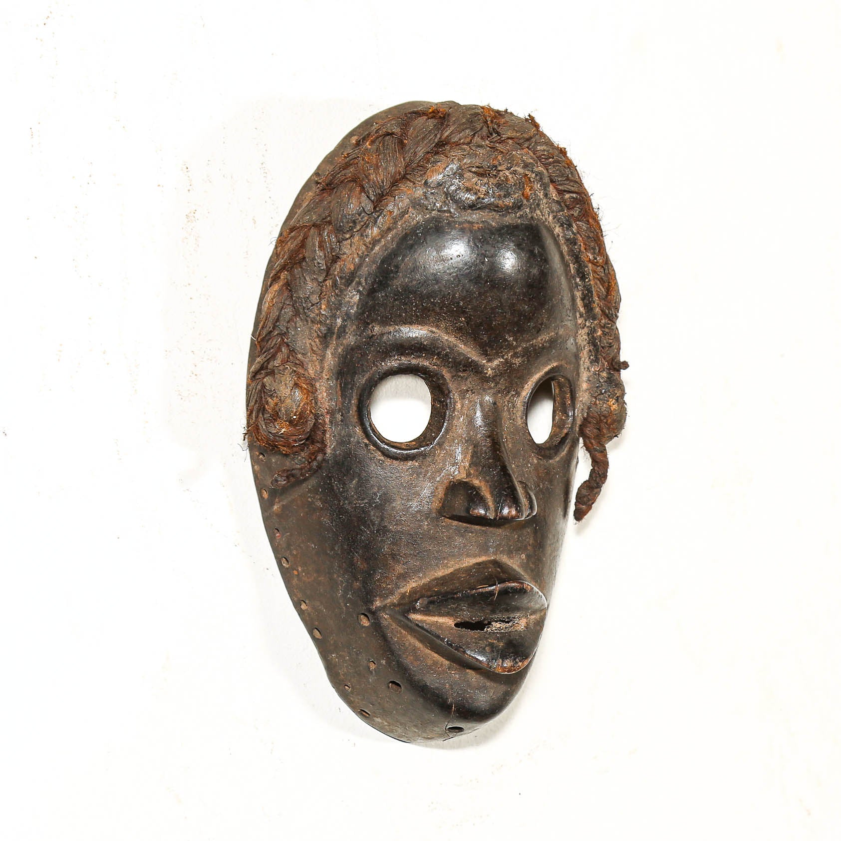 Traditional wooden mask with braided hair on a white background